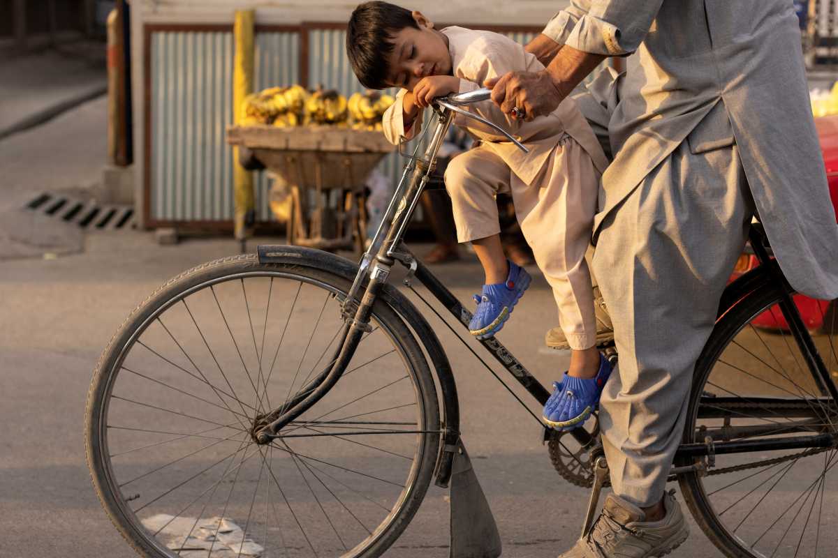 A boy sleeps as he rides a bicycle in Kabul, Afghanistan October 18, 2021. REUTERS