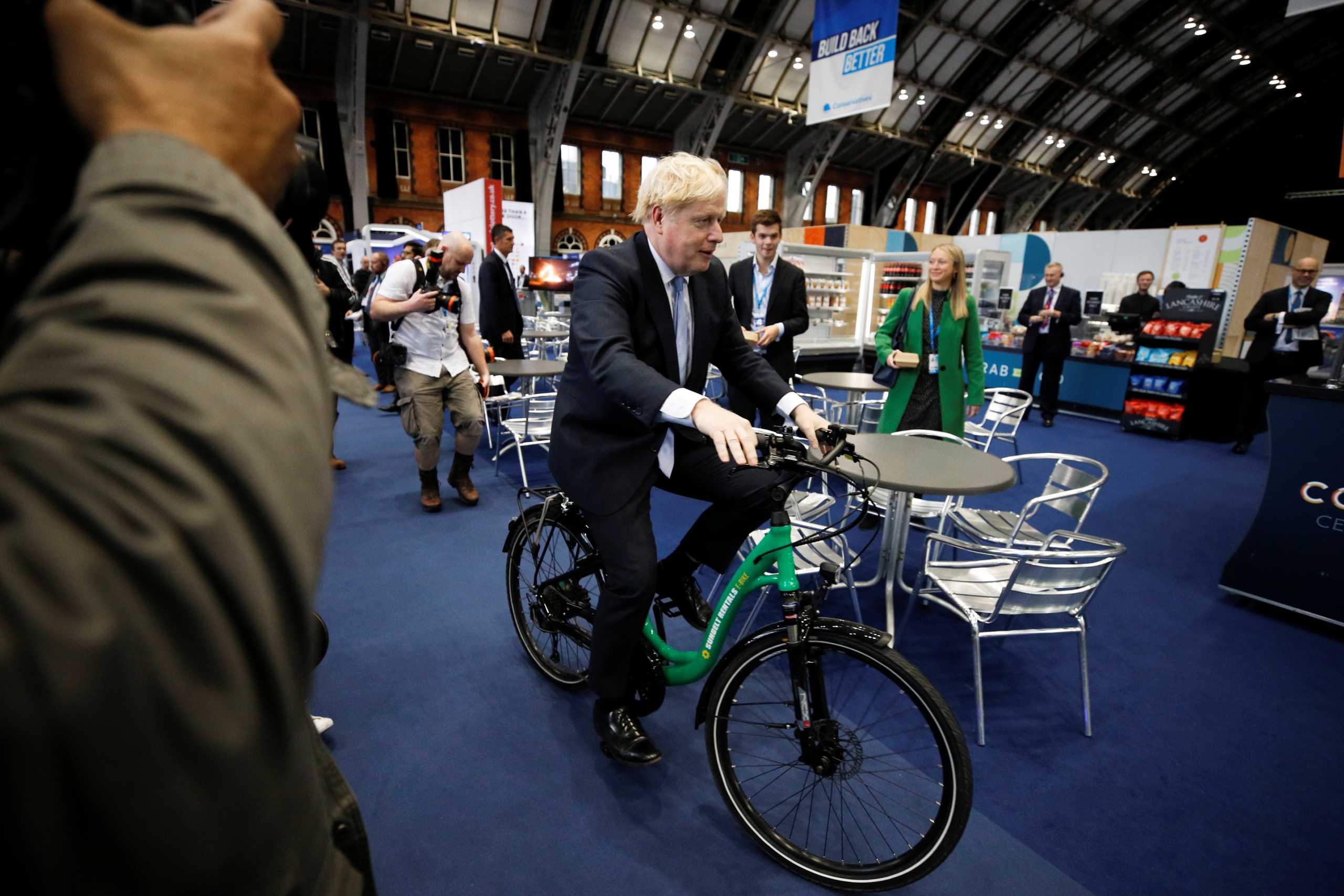 Britain's Prime Minister Boris Johnson sits on a bike as he visits a trade stall inside the conference venue at the annual Conservative Party conference, in Manchester, Britain, October 5, 2021. REUTERS