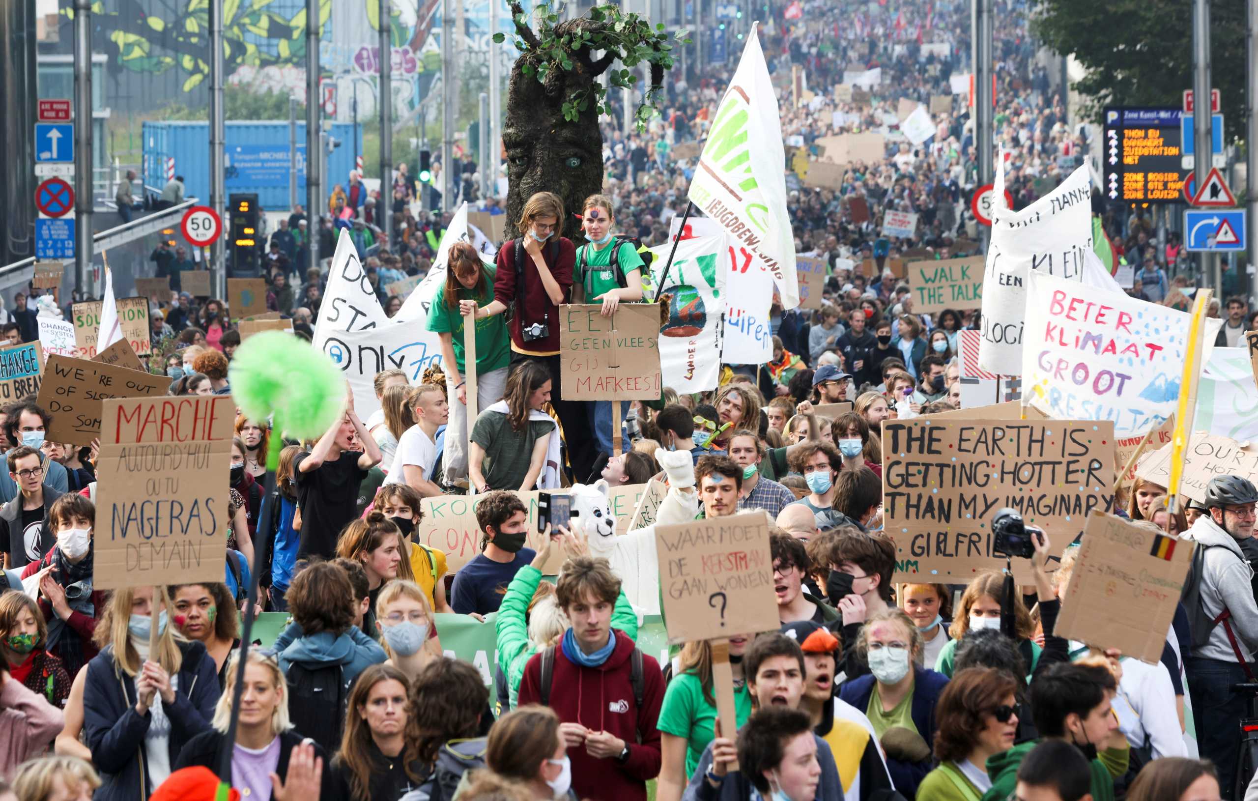People hold placards as they take part in a Climate March ahead of the COP26 climate summit, in Brussels, Belgium October 10, 2021. REUTERS