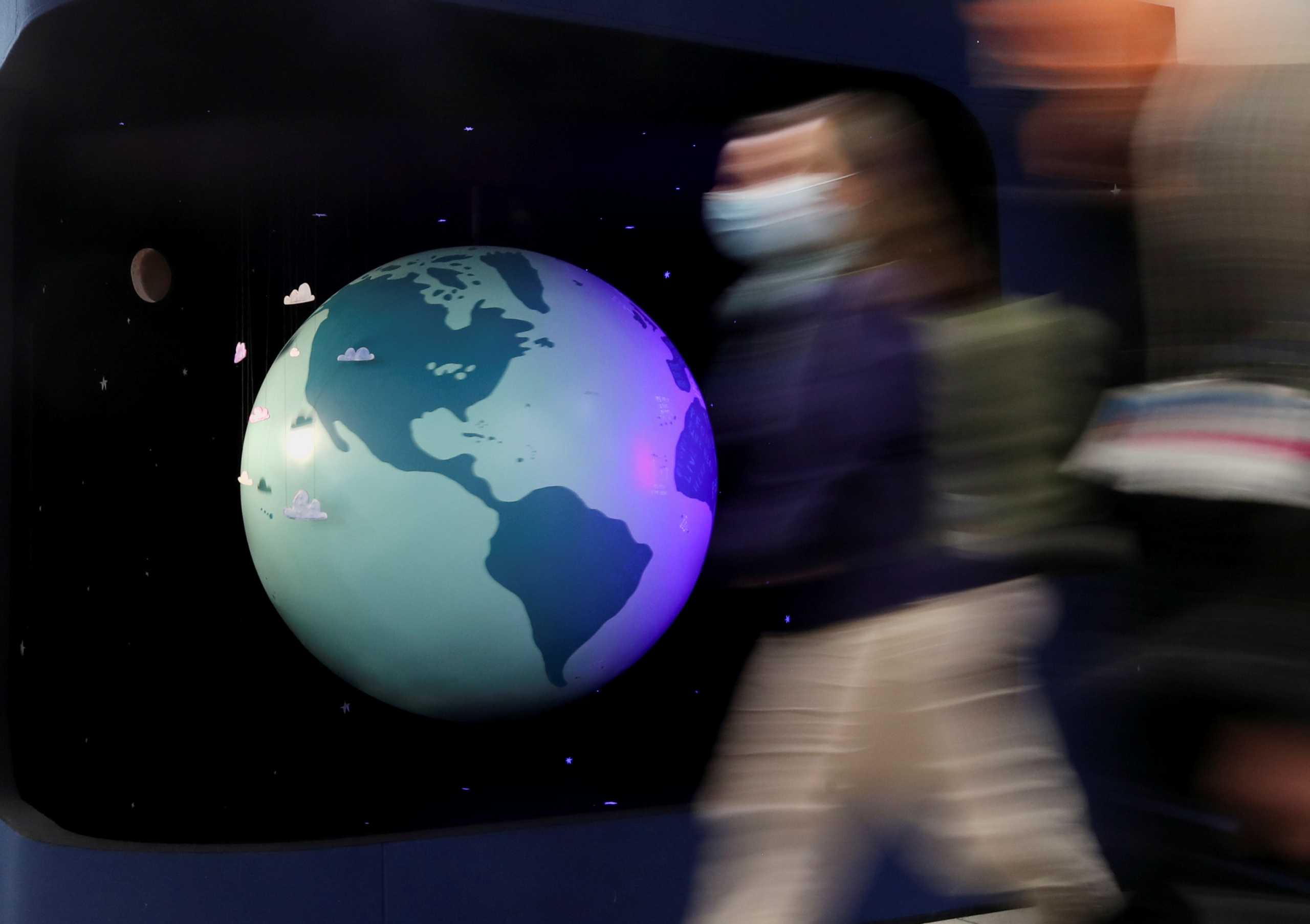 People walk past a mode of the earth during the UN Climate Change Conference (COP26) in Glasgow, Scotland, Britain, October 31, 2021.  REUTERS