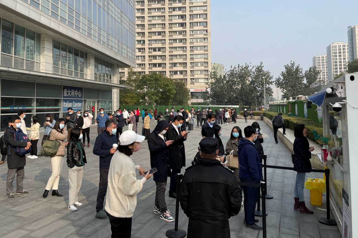 People queue to take a nucleic acid test at a booth on the street outside a shopping mall, following new cases of the coronavirus disease (COVID-19), in Beijing, China, October 25, 2021. REUTERS