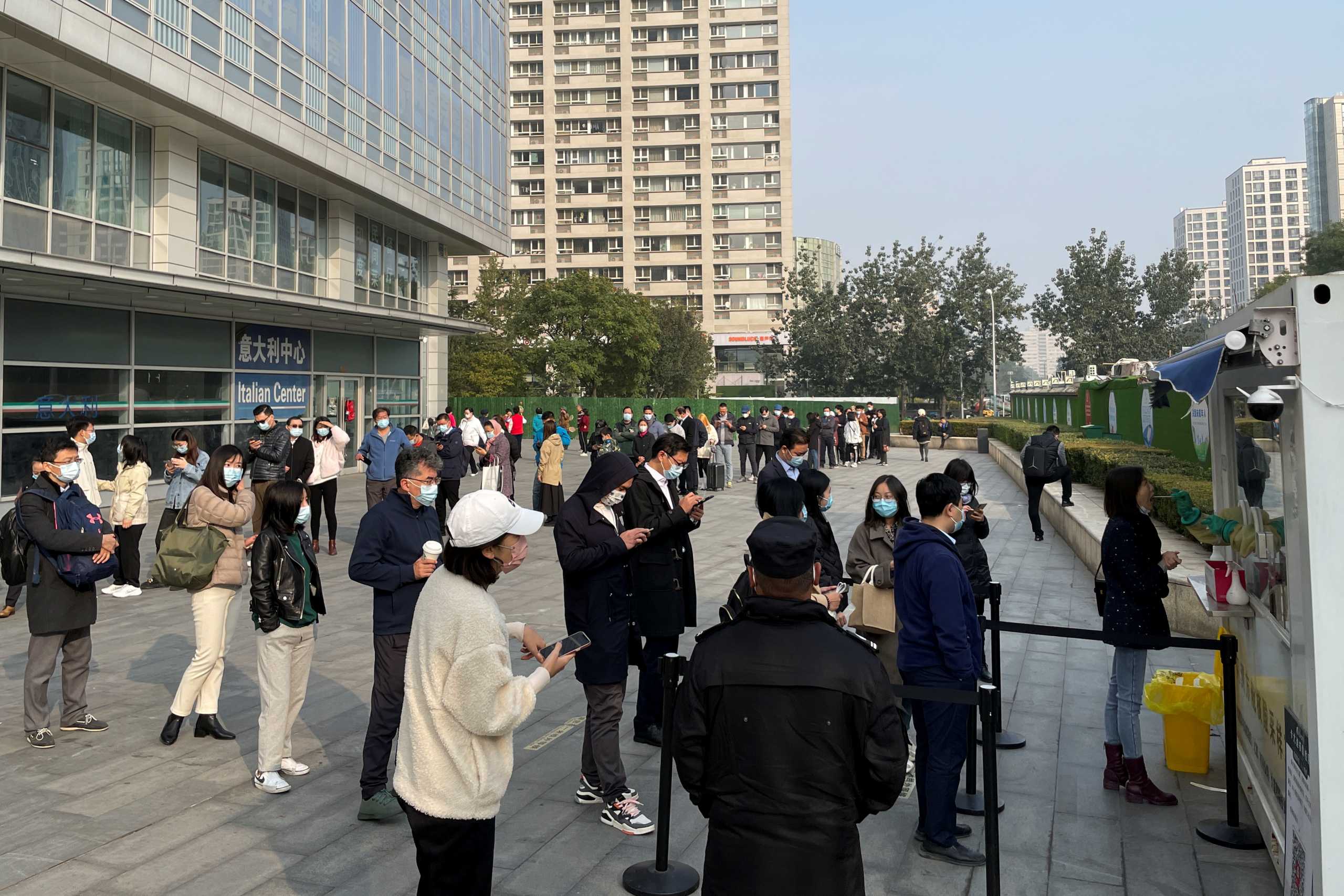 People queue to take a nucleic acid test at a booth on the street outside a shopping mall, following new cases of the coronavirus disease (COVID-19), in Beijing, China, October 25, 2021. REUTERS