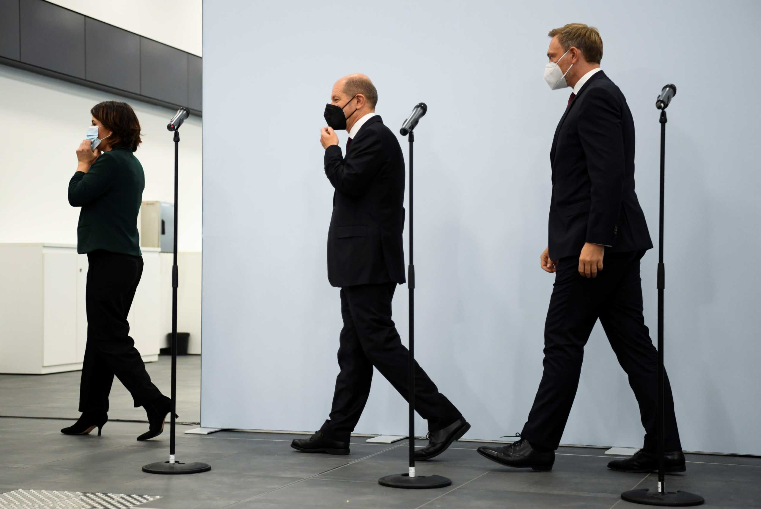 Germany's Greens party co-leader Annalena Baerbock, Social Democratic Party (SPD) top candidate for chancellor Olaf Scholz and Free Democratic Party (FDP) leader Christian Lindner leave after a statement following a meeting for exploratory talks for a possible new government coalition in Berlin, Germany, October 15, 2021. REUTERS