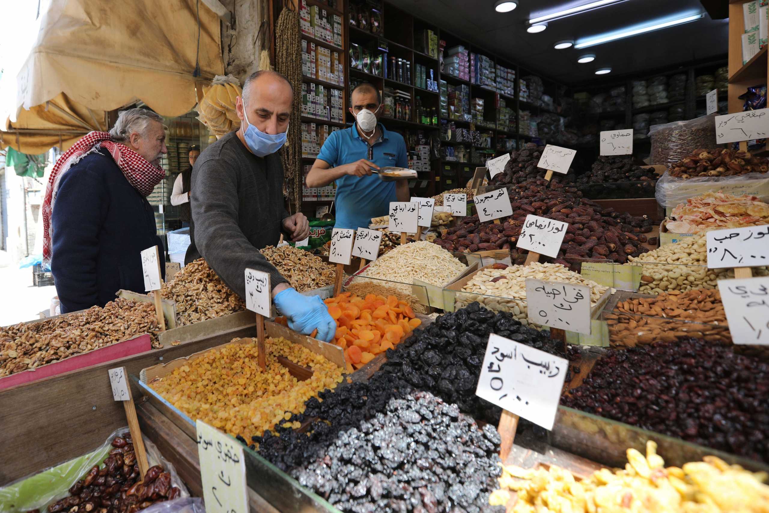Vendors wearing protective face masks serve customers at a shop, ahead of the Muslim holy month of Ramadan, amid concerns over the coronavirus disease (COVID-19), in Amman, Jordan April 21, 2020. Picture taken April 21, 2020. REUTERS