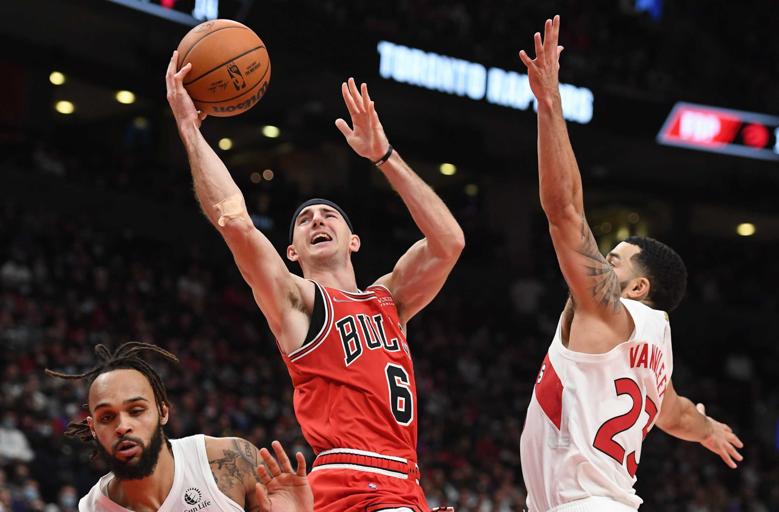 Oct 25, 2021; Toronto, Ontario, CAN; Chicago Bulls guard Alex Caruso (6) drives to the basket between Toronto Raptors guards Fred Van Vleet (23) and Gary Trent Jr. (33)  in the second half at Scotiabank Arena. Mandatory Credit: Dan Hamilton-USA TODAY Sports