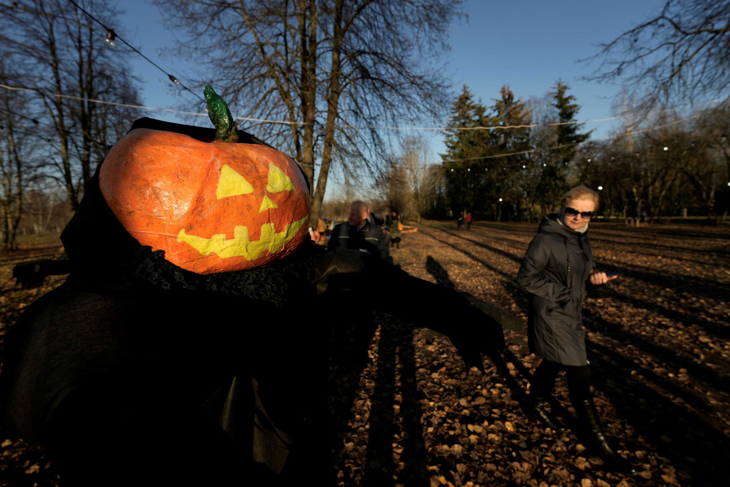 People walk past a Halloween character with pumpkin head during a Halloween festival in Kirkilai amusement park near Birzai, Lithuania October 30, 2021. REUTERS