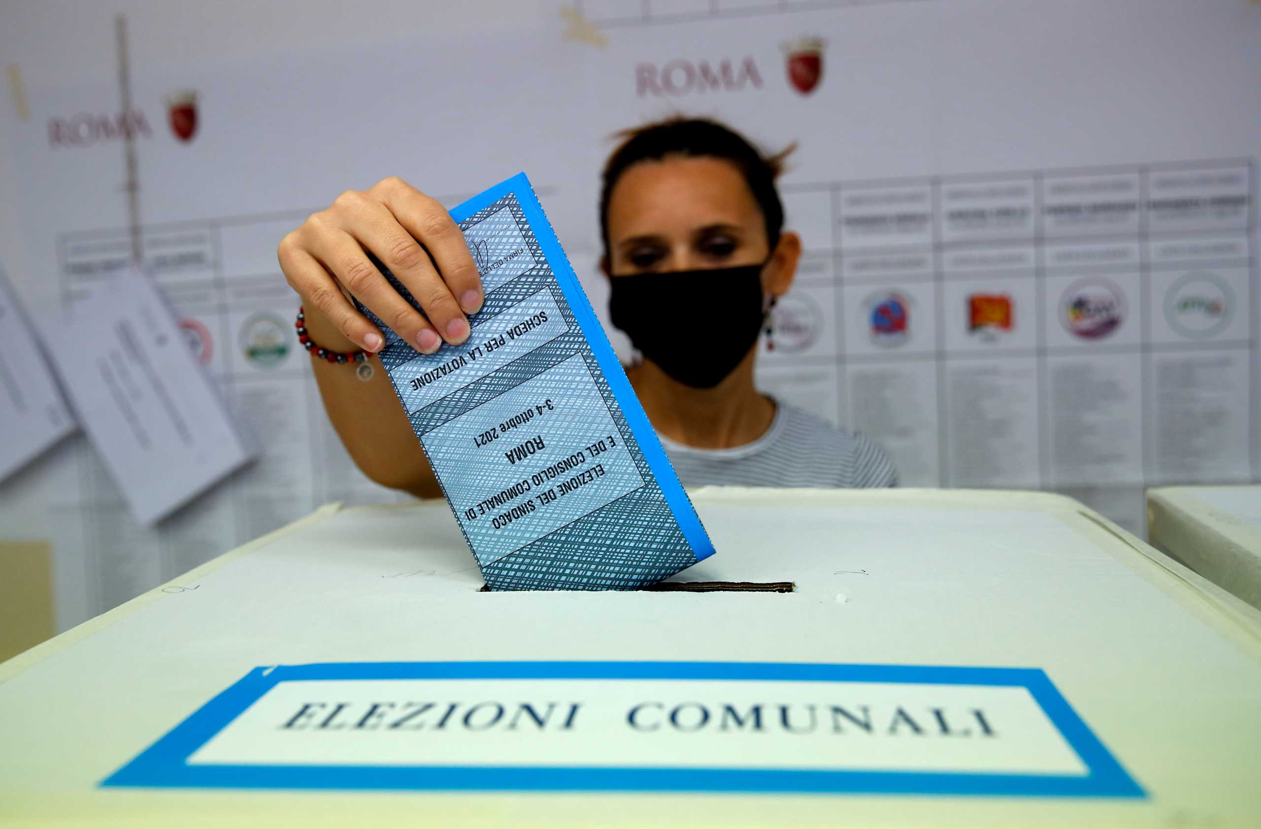 FILE PHOTO: A person casts a vote during Italian elections for mayors and councillors, in Rome, Italy, October 3, 2021. REUTERS