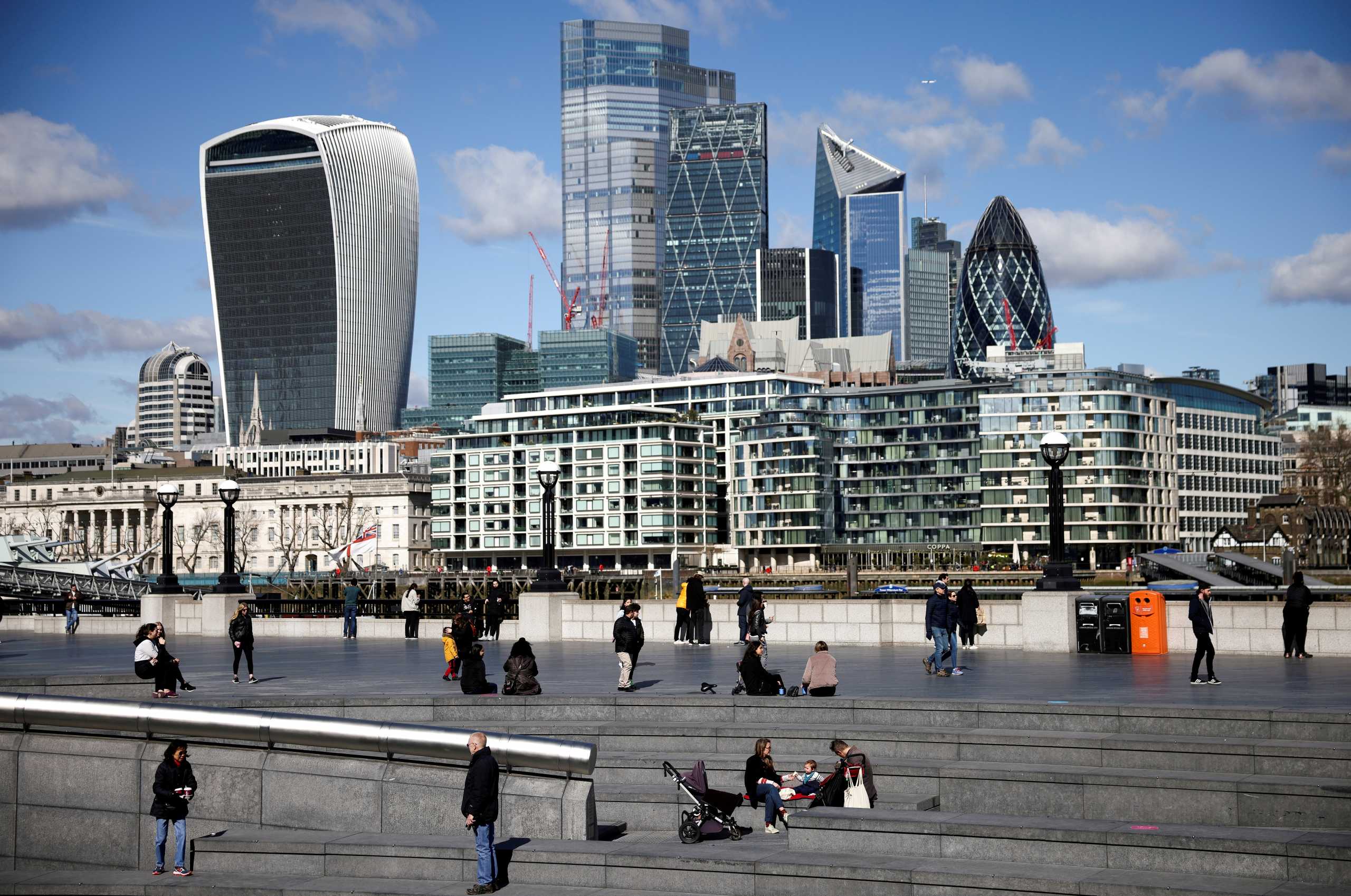 FILE PHOTO: The City of London financial district can be seen as people walk along the south side of the River Thames, amid the coronavirus disease (COVID-19) outbreak in London, Britain, March 19, 2021. REUTERS