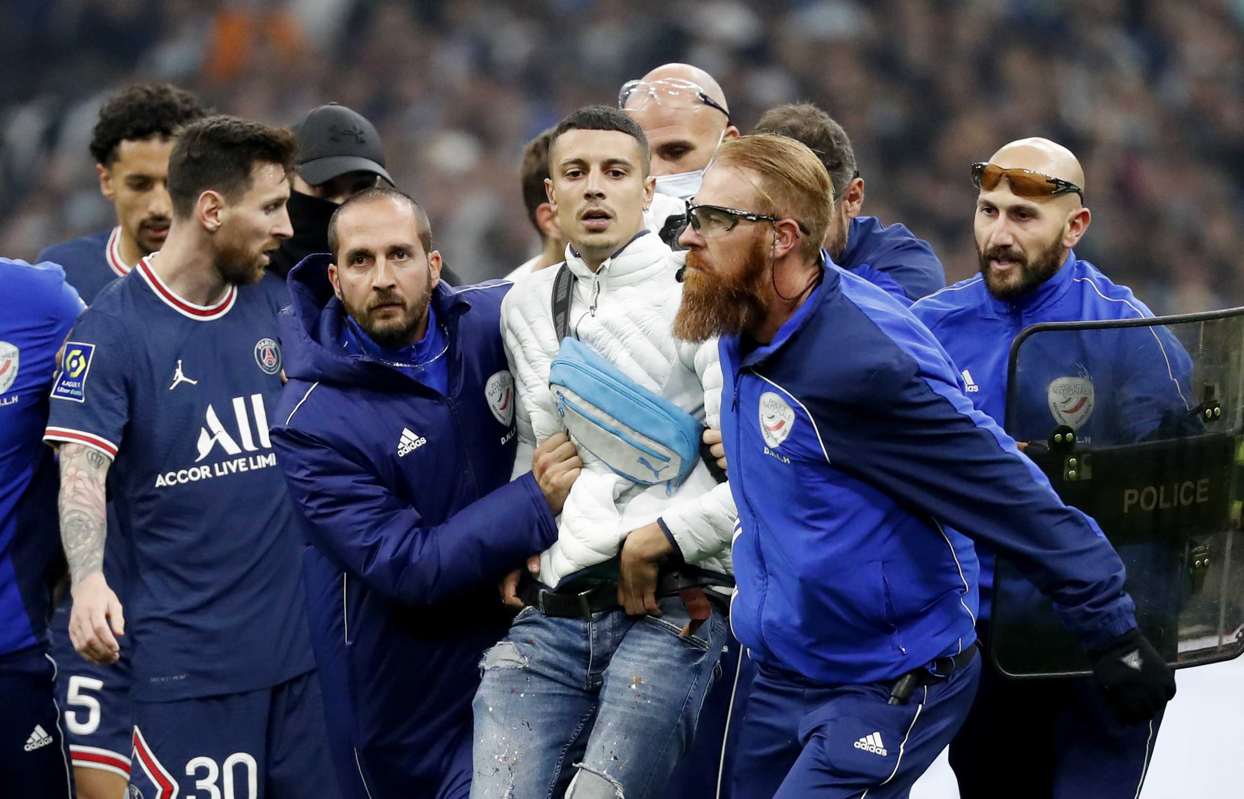 Soccer Football - Ligue 1 - Olympique de Marseille v Paris St Germain - Orange Velodrome, Marseille, France - October 24, 2021 Paris St Germain's Lionel Messi reacts as a pitch invader is detained by stewards REUTERS
