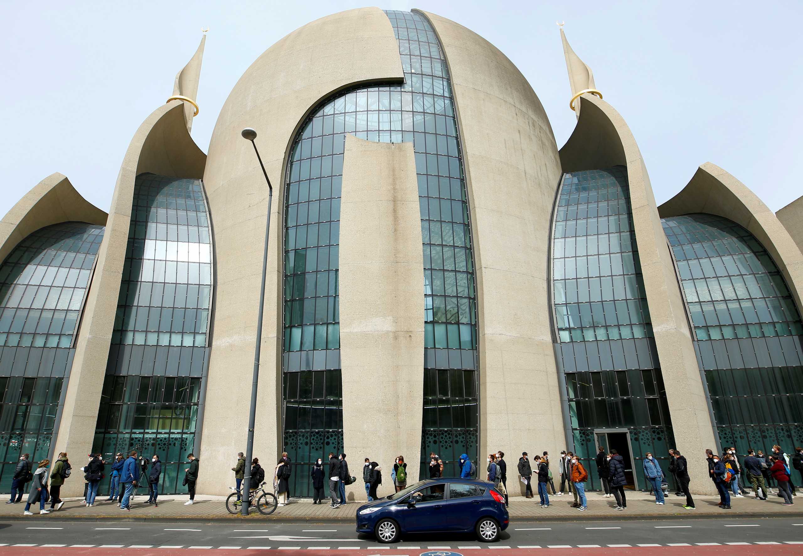 FILE PHOTO: People queue in front of the Central Mosque in Ehrenfeld suburb, as they wait for a COVID-19 vaccination, amid the coronavirus disease (COVID-19) pandemic, in Cologne, Germany, May 8, 2021. REUTERS