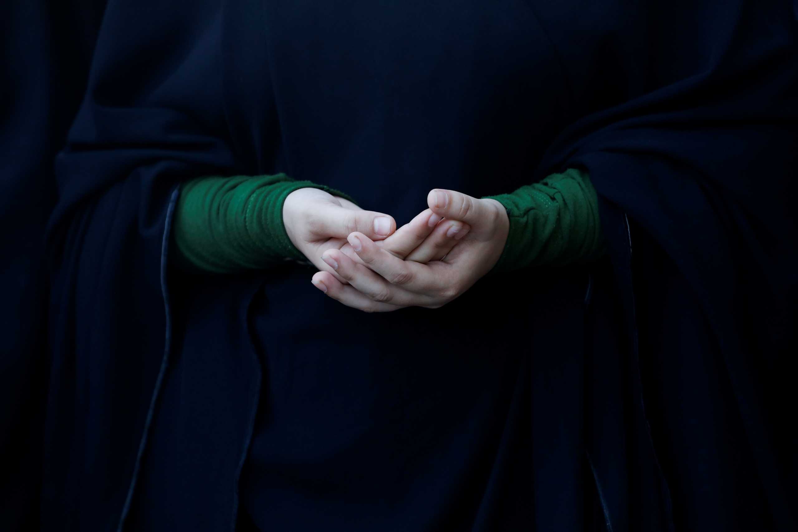 A Shiite Muslim woman participant holds her hands as she prays to condemn the suicide bombings on Shiite mosques in Afghanistan, during a protest rally in Karachi, Pakistan, October 17, 2021. REUTERS