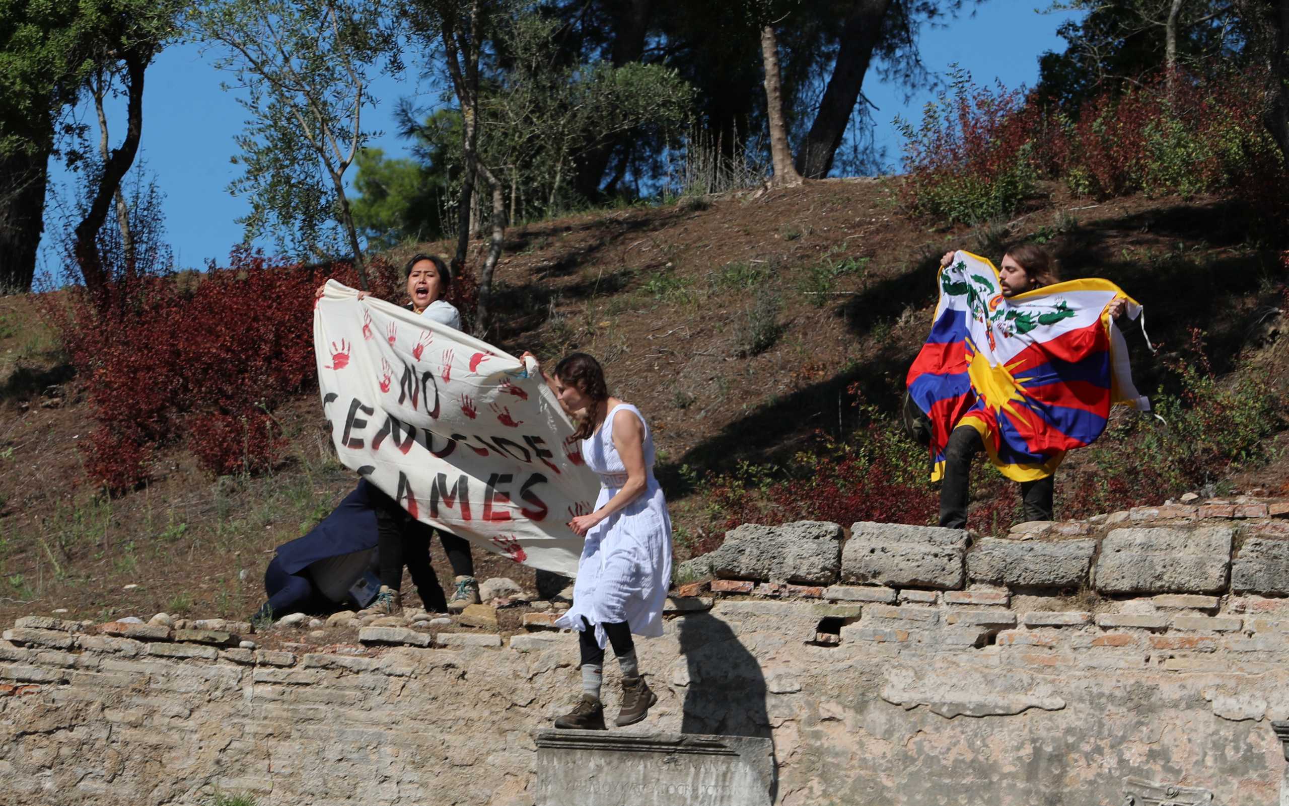 Winter Olympics - Lighting ceremony of the Olympic flame for the Beijing 2022 Winter Olympics - Ancient Olympia, Olympia, Greece - October 18, 2021 Protesters hold a Tibetan flag and a banner during the Olympic flame lighting ceremony for the Beijing 2022 Winter Olympics REUTERS