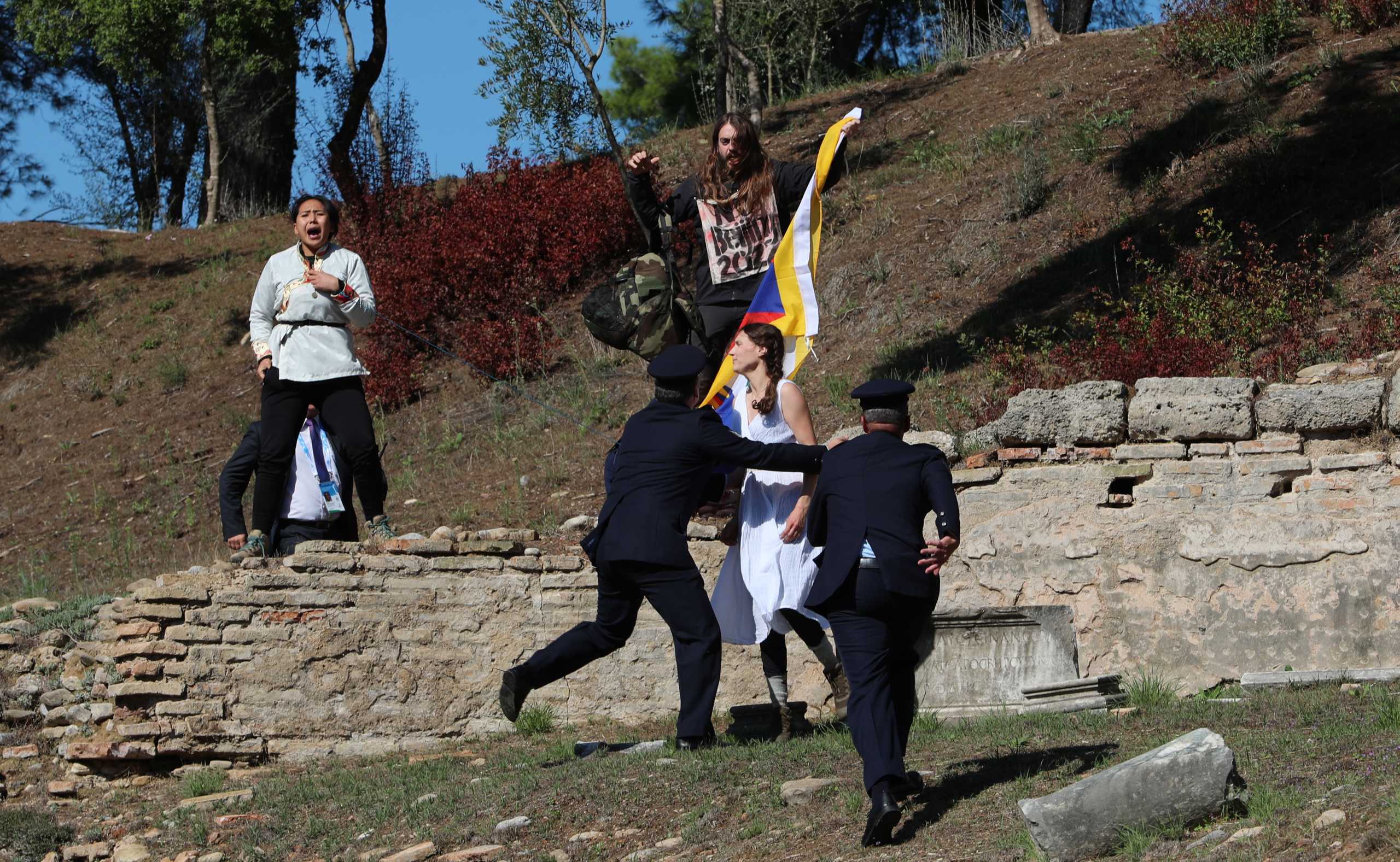Winter Olympics - Lighting ceremony of the Olympic flame for the Beijing 2022 Winter Olympics - Ancient Olympia, Olympia, Greece - October 18, 2021 A protester holds a Tibetan flag as security officers intervene during the Olympic flame lighting ceremony for the Beijing 2022 Winter Olympics REUTERS