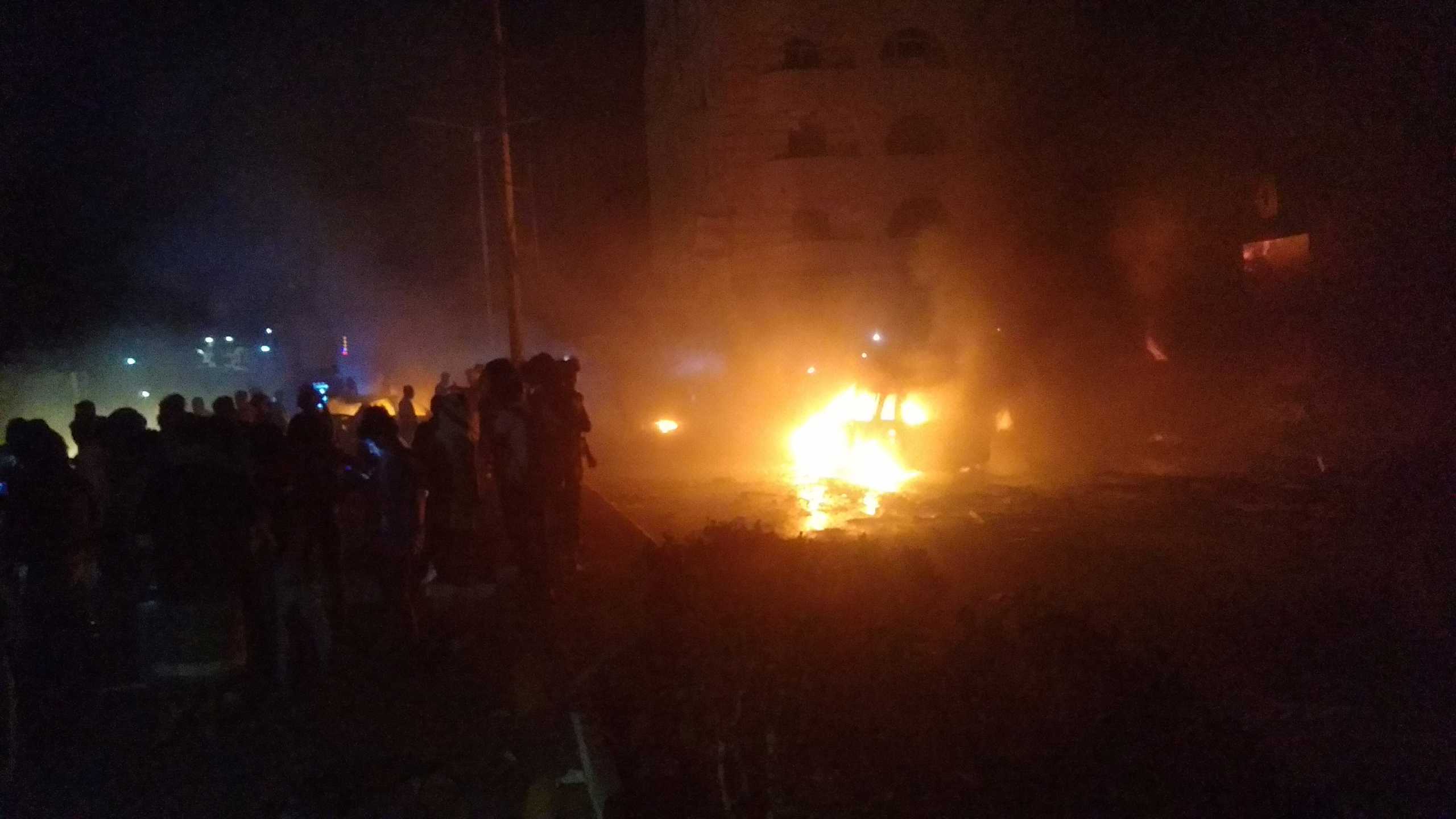 People look at cars on fire at the site of an explosion outside Aden international airport in Aden, Yemen, October 30, 2021. REUTERS