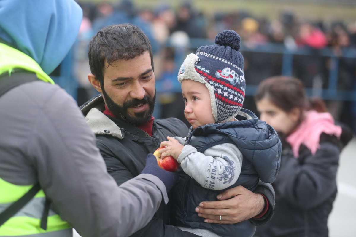 A child holds an apple during the distribution of humanitarian aid among migrants near Bruzgi - Kuznica checkpoint on the Belarusian-Polish border in the Grodno region, Belarus November 17, 2021. Leonid Scheglov