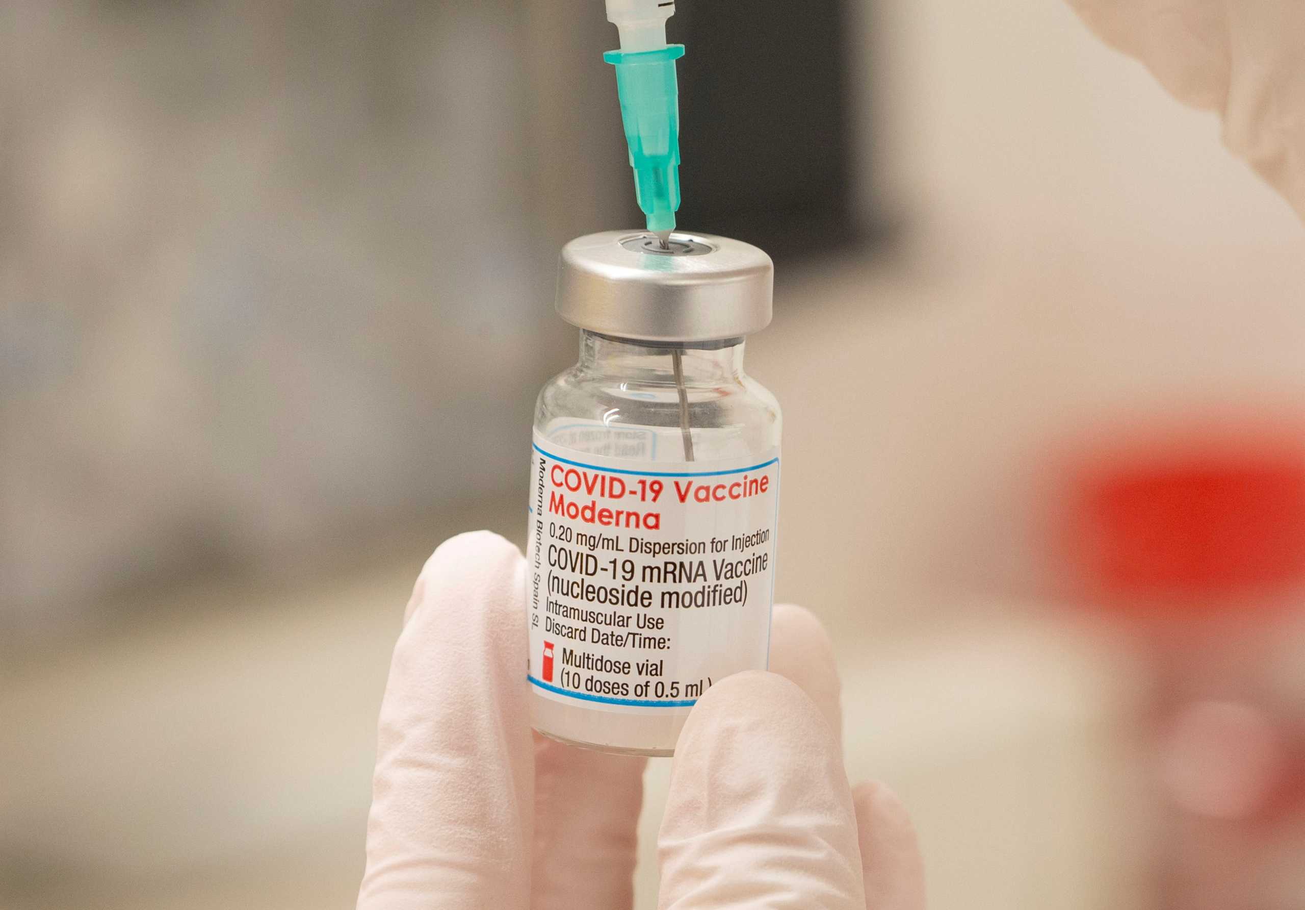 FILE PHOTO: A health care worker fills up a syringe with a dose of Moderna's COVID-19 vaccine for a booster shot at the vaccination reference center at the Epidemiology, Biostatistics and Prevention Institute (EBPI) in Zurich, Switzerland November 17, 2021. REUTERS