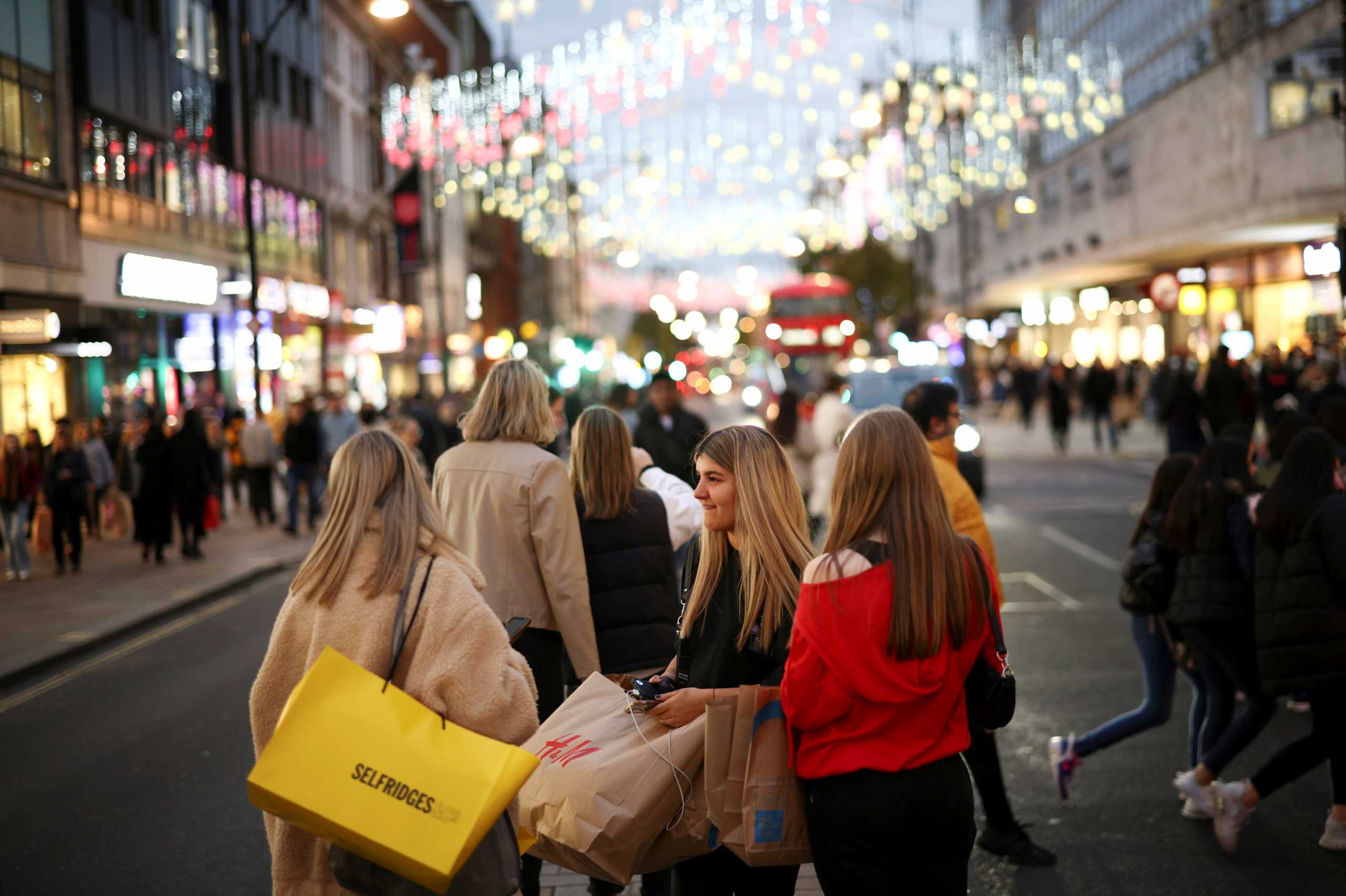 FILE PHOTO: People with shopping bags walk along Oxford Street illuminated with Christmas lights in London, Britain, November 13, 2021. REUTERS