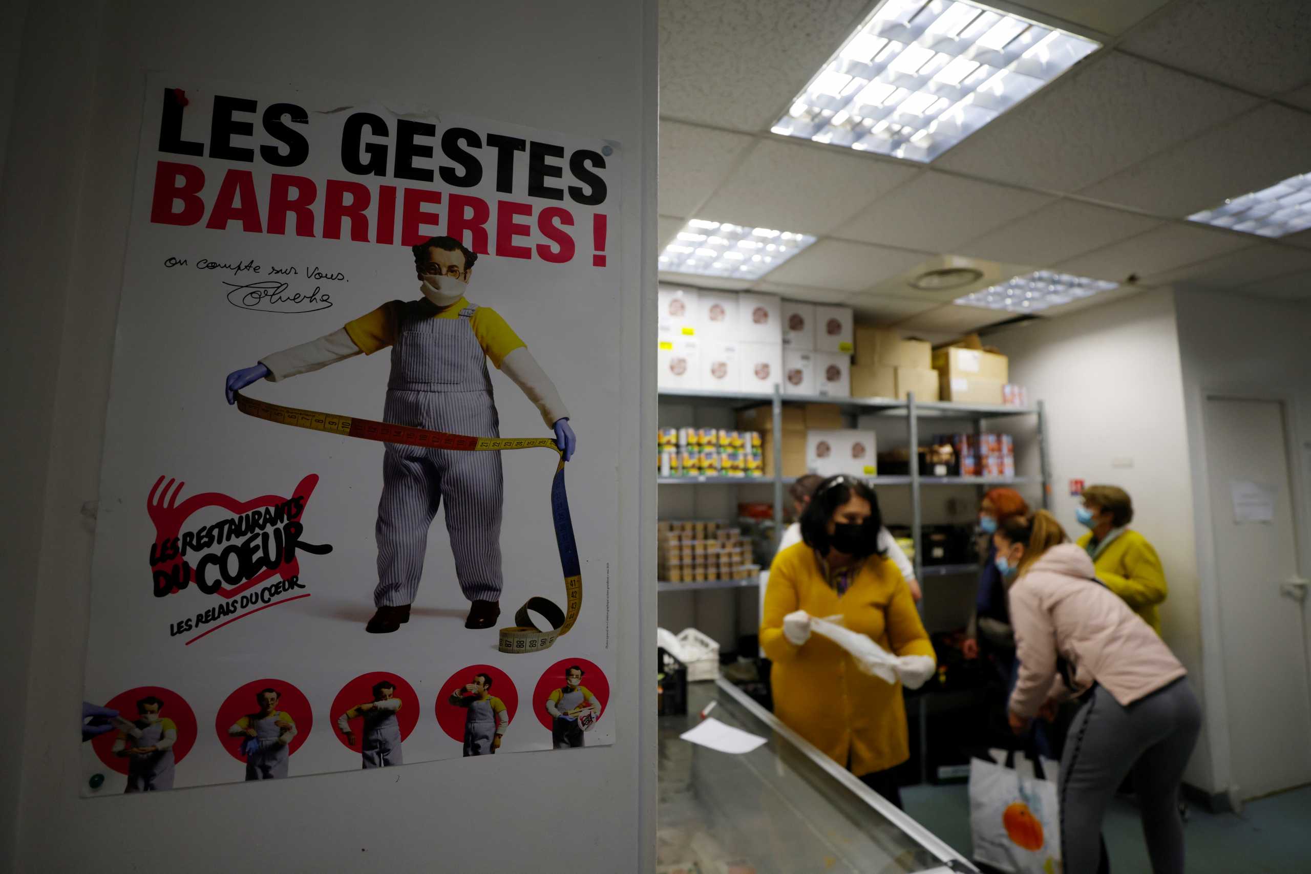 A picture of late French comic Coluche is seen as a volunteer gives food to a woman in a charity food distribution centre "Les Restos Du Coeur" (Restaurants of the Heart) in Nice, France, November 22, 2021.  REUTERS