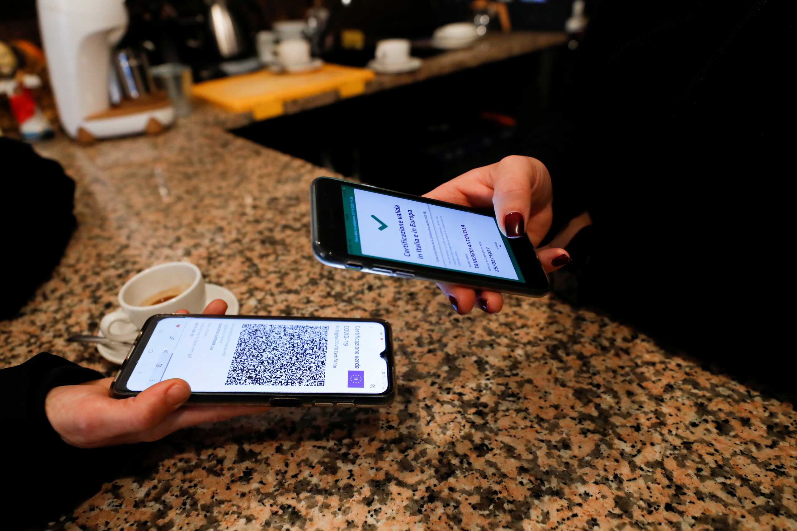 A customer has her coronavirus disease (COVID-19) health pass, known as a Green Pass, checked as she arrives at a bar, in Rome, Italy November 23, 2021. REUTERS