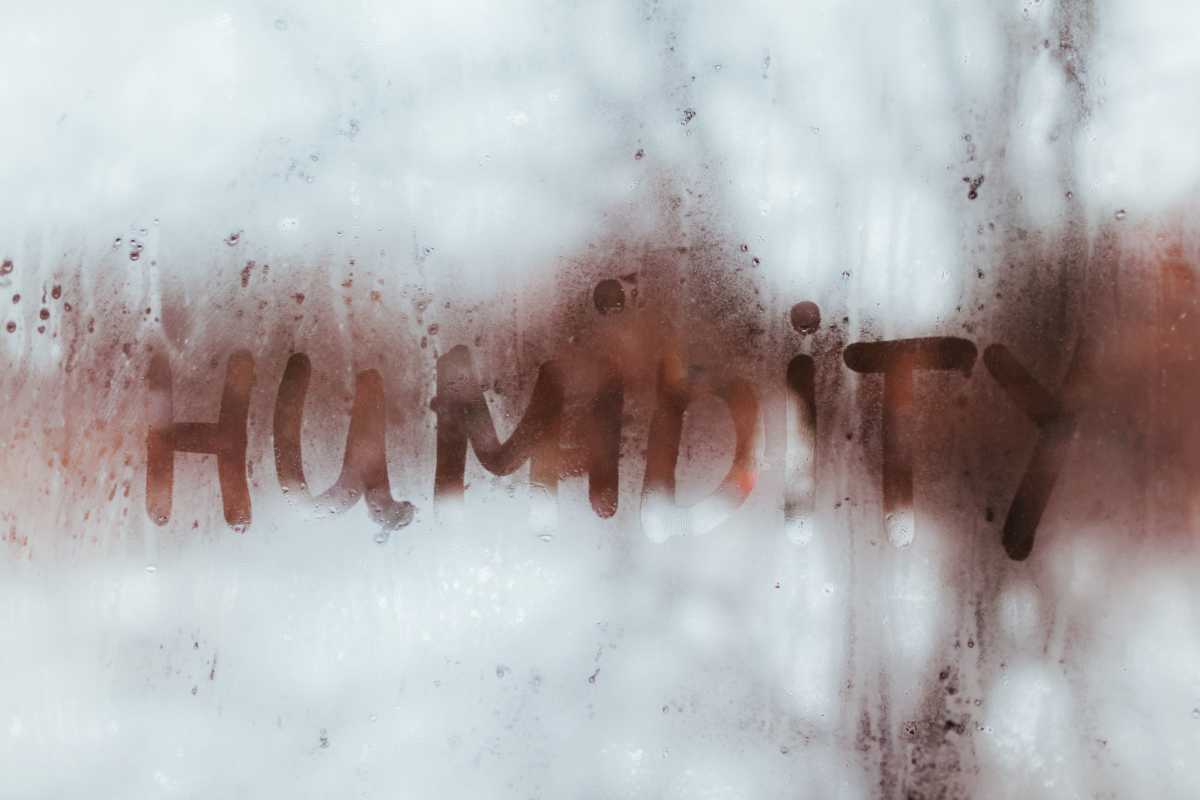Humidity word written on wet window with condensate. High level of dampness in apartment.