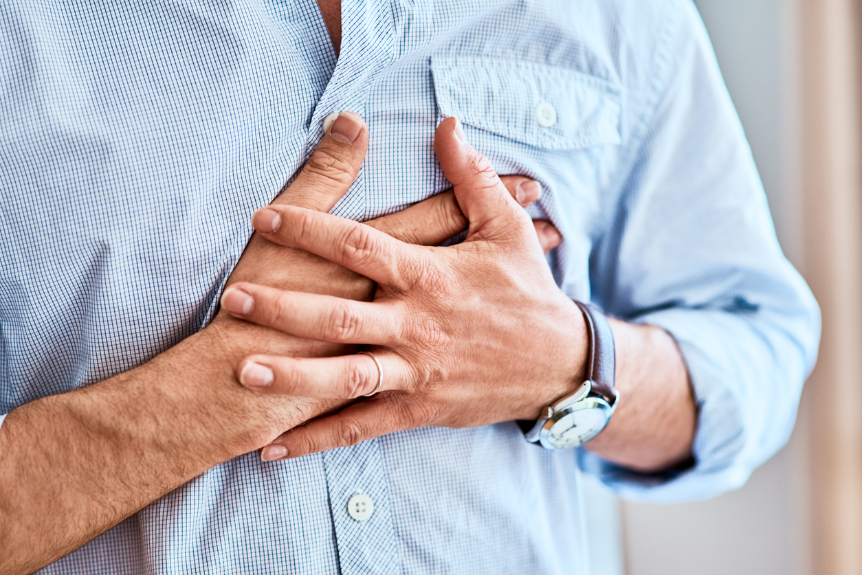 Shot of a unrecognizable man holding his chest in discomfort due to pain at home during the day