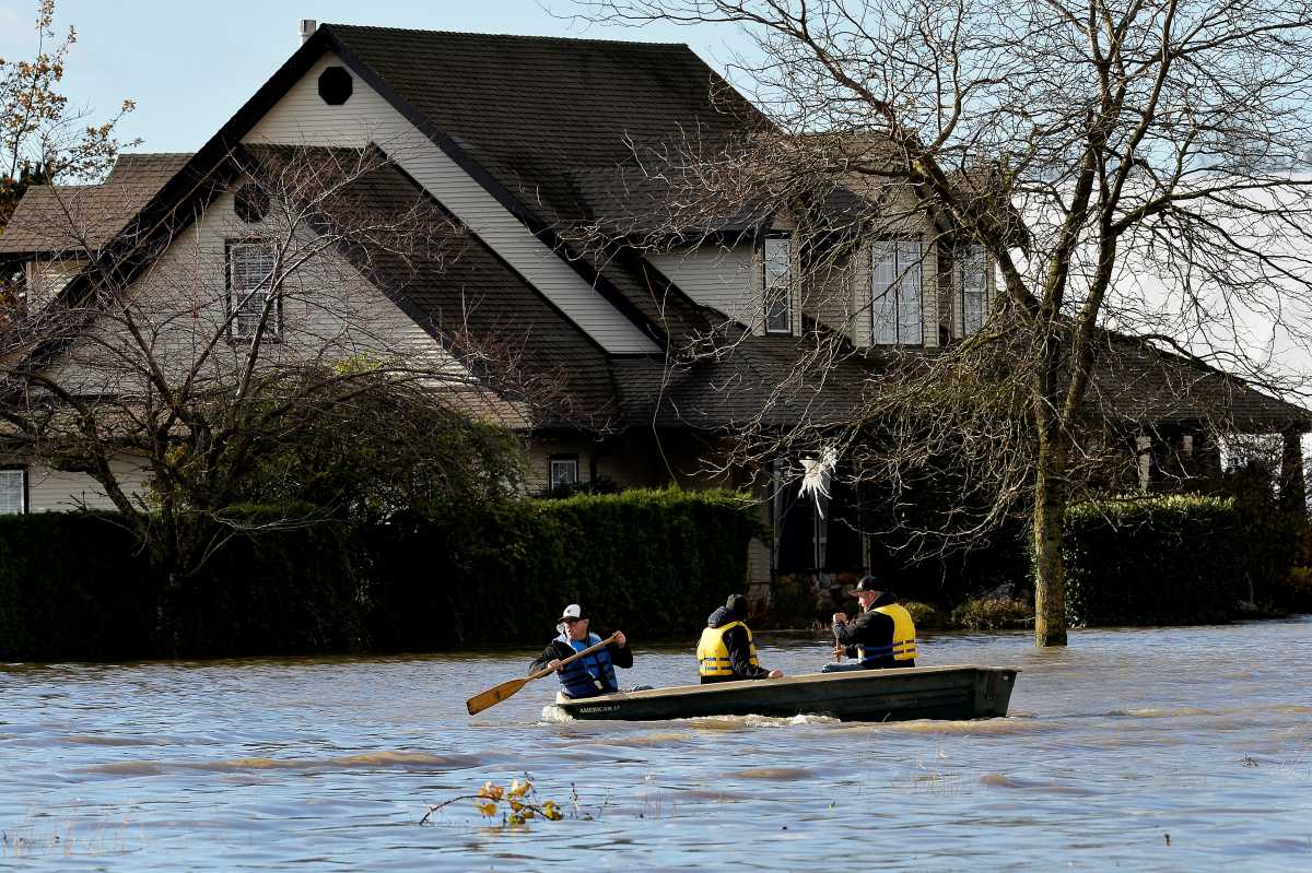 Three men paddle on a flooded road after rainstorms caused flooding and landslides in Abbotsford, British Columbia, Canada November 16, 2021.  REUTERS