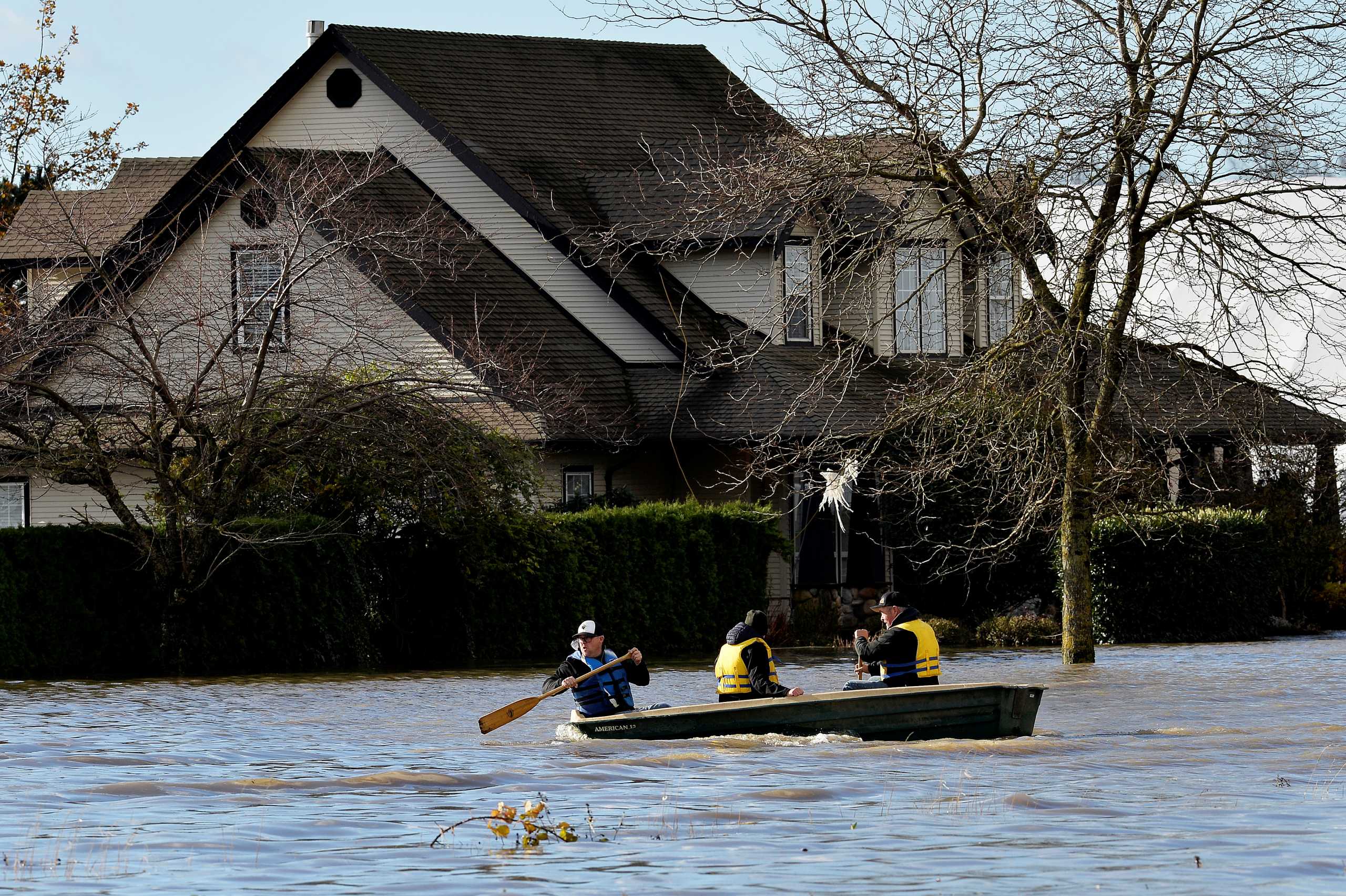 Three men paddle on a flooded road after rainstorms caused flooding and landslides in Abbotsford, British Columbia, Canada November 16, 2021.  REUTERS