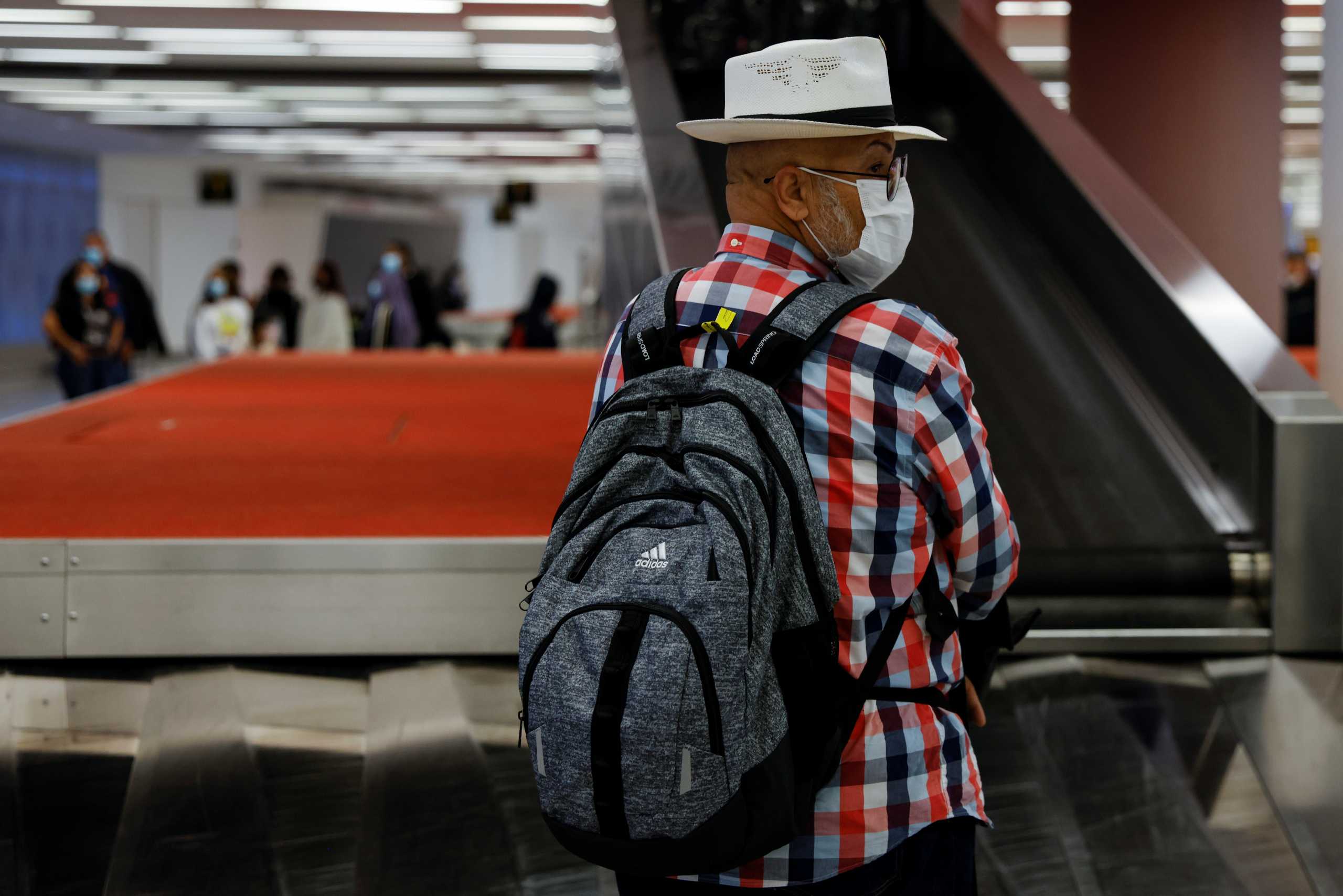 A man wearing a protective face mask, amid the coronavirus disease (COVID-19) pandemic, waits at the JetBlue baggage claim area of JFK International airport in New York, U.S., November 16, 2021. REUTERS