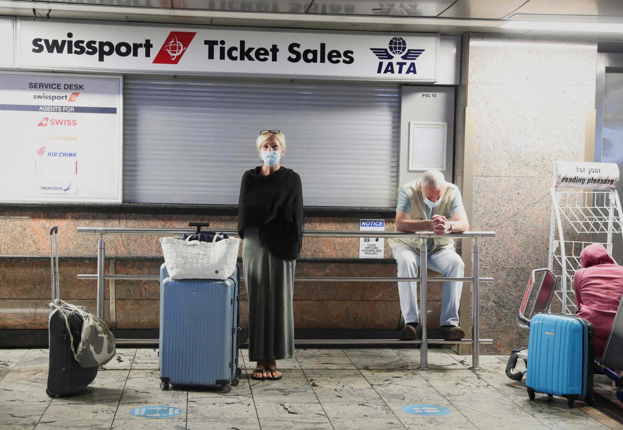 Passengers wait for confirmation of flights outside the Swissport Ticket Sales counter as several airlines stopped flying out of South Africa, amidst the spread of the new SARS-CoV-2 variant Omicron, at O.R. Tambo International Airport in Johannesburg, South Africa, November 28, 2021. REUTERS