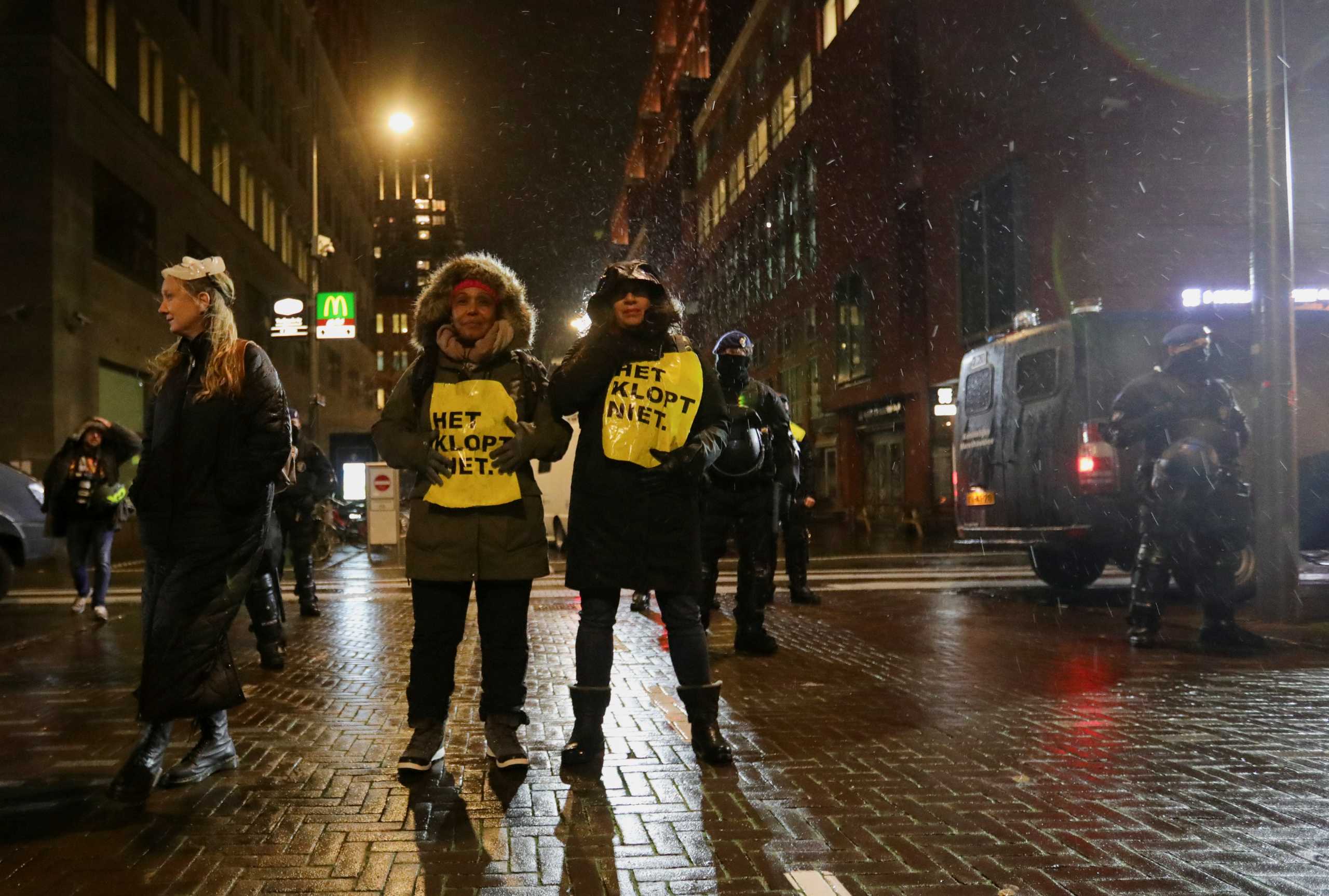 Demonstrators wear signs reading "It is not right" while police officers stand guard following Dutch Prime Minister Mark Rutte's announcement of new measures to fight a record surge in coronavirus disease (COVID-19) infections, in The Hague, Netherlands, November 26, 2021. REUTERS