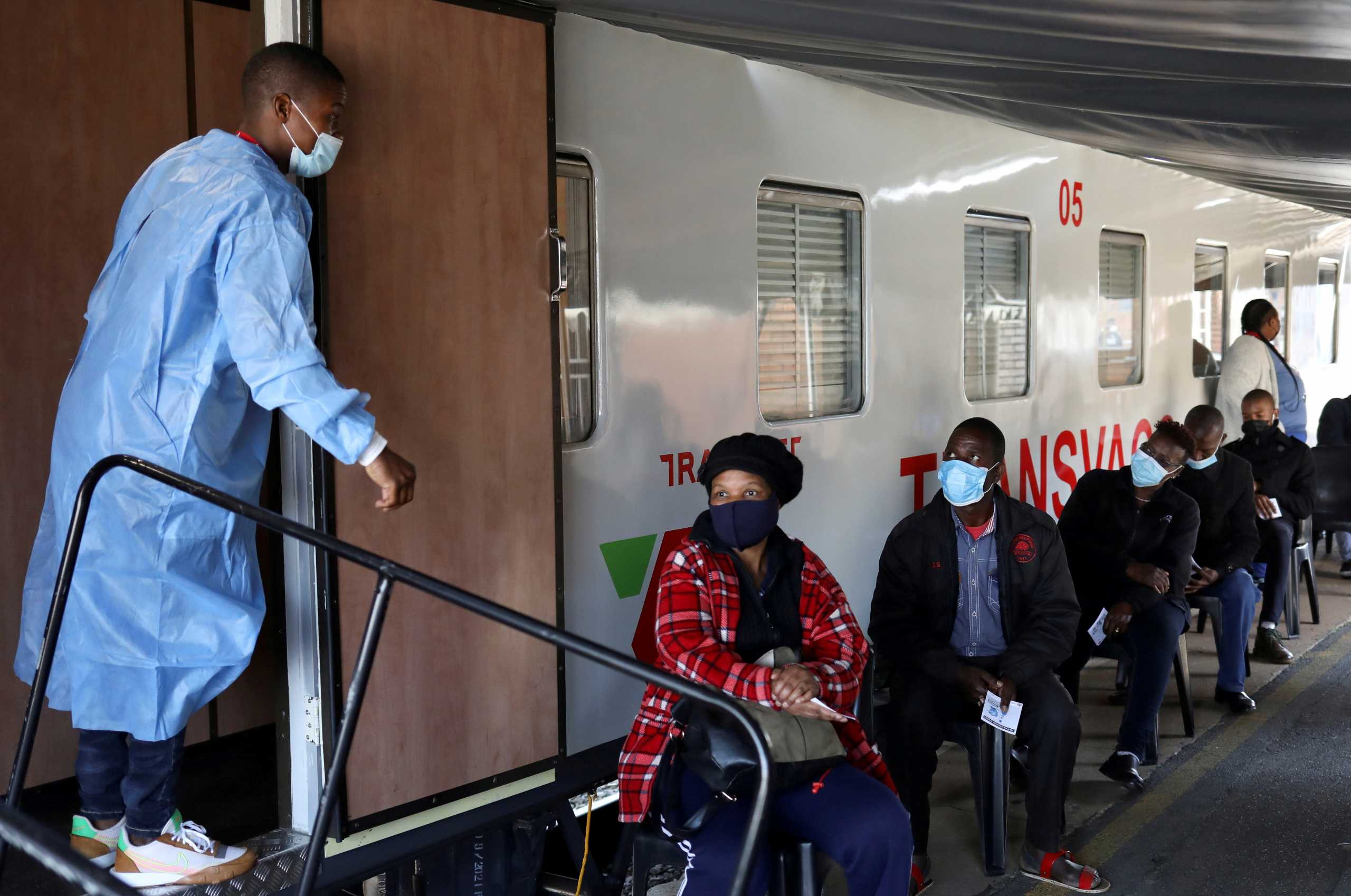 FILE PHOTO: FILE PHOTO: A health worker talks to people as they wait to register next to the Transvaco coronavirus disease (COVID-19) vaccine train, after South Africa's rail company Transnet turned the train into a COVID-19 vaccination center on rails to help the government speed up its vaccine rollout in the country's remote communities, at the Springs train station on the East Rand, South Africa, August 30, 2021. REUTERS