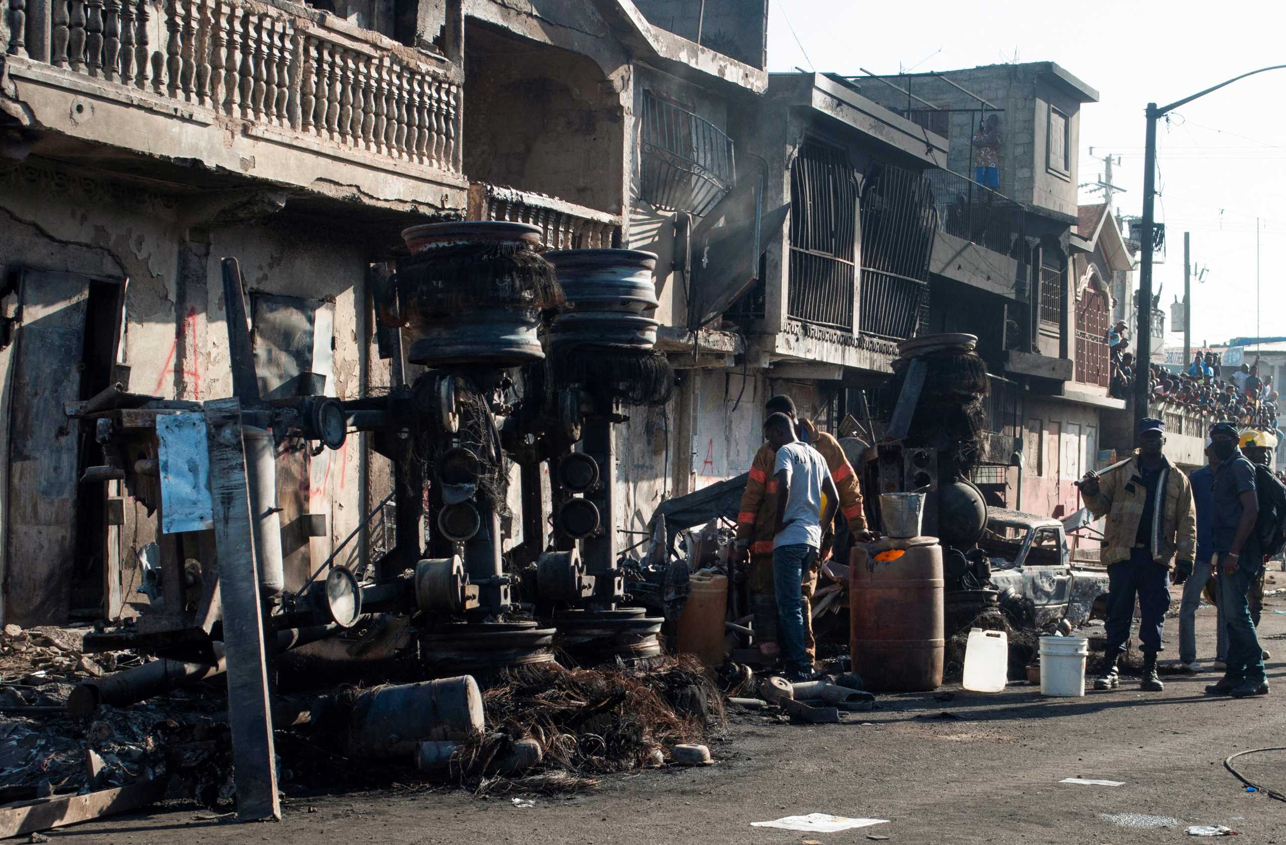 Firefighters and police officers stand next to the remains of a burnt fuel truck after the truck exploded in a neighbourhood during the night in Cap Haitien, Haiti December 14, 2021.  REUTERS