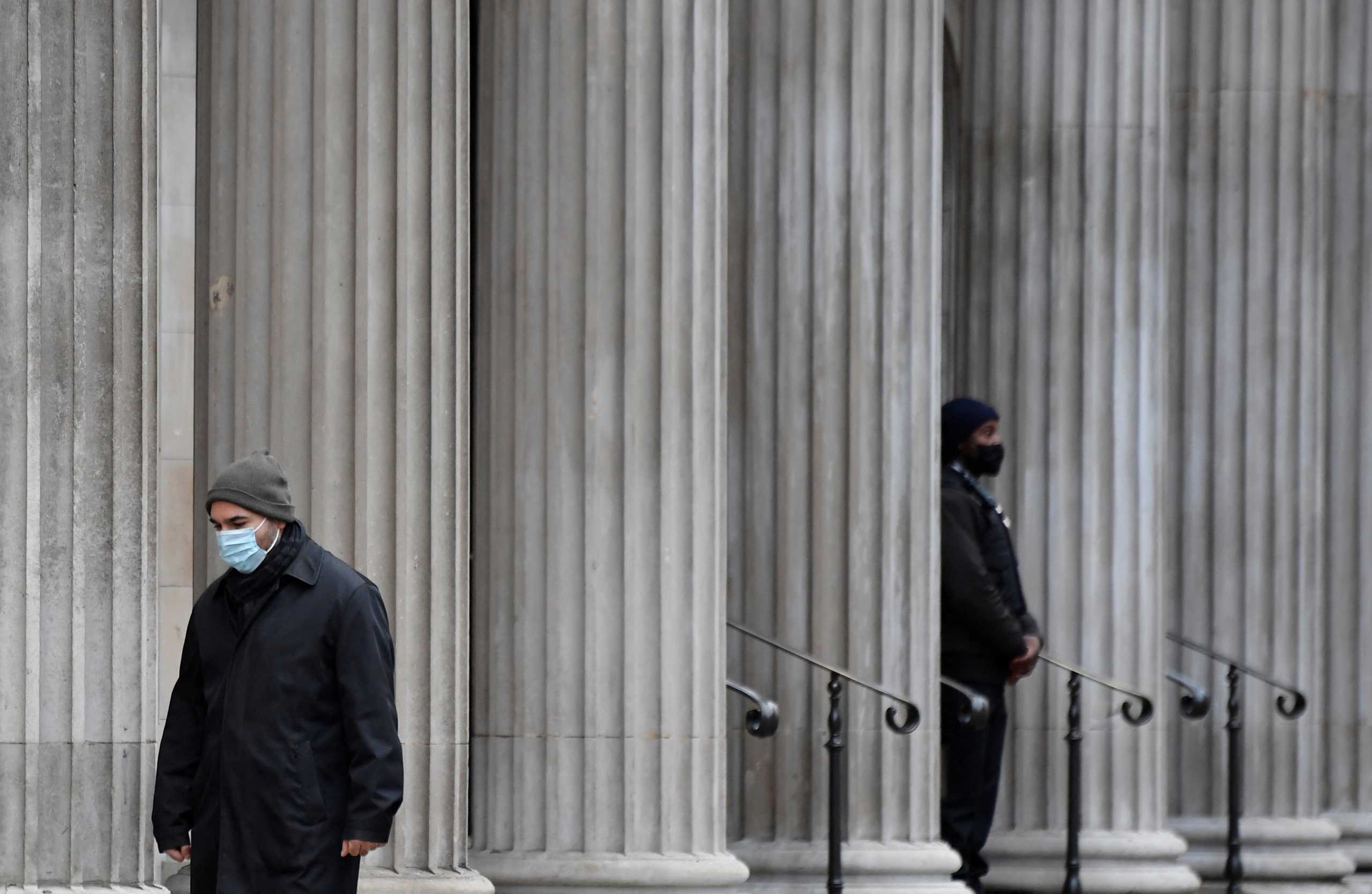A man wearing a protective face mask walks past the Bank of England (BoE), after the BoE became the first major world's central bank to raise rates since the coronavirus disease (COVID-19) pandemic, London, Britain, December 16, 2021. REUTERS