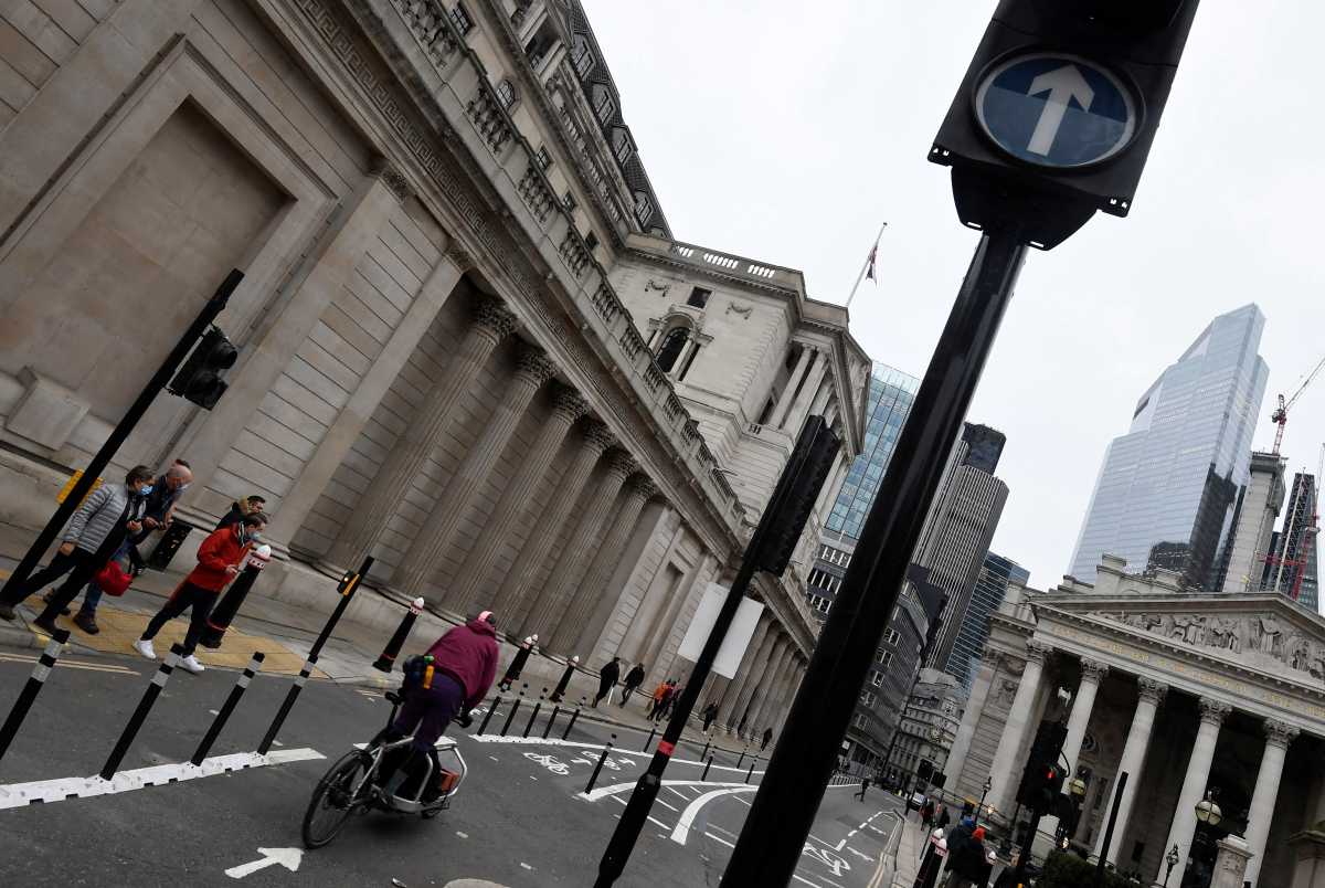 People cross a road in front of the Bank of England (BoE) building after the BoE became the first major world's central bank to raise rates since the coronavirus disease (COVID-19) pandemic, London, Britain, December 16, 2021. REUTERS