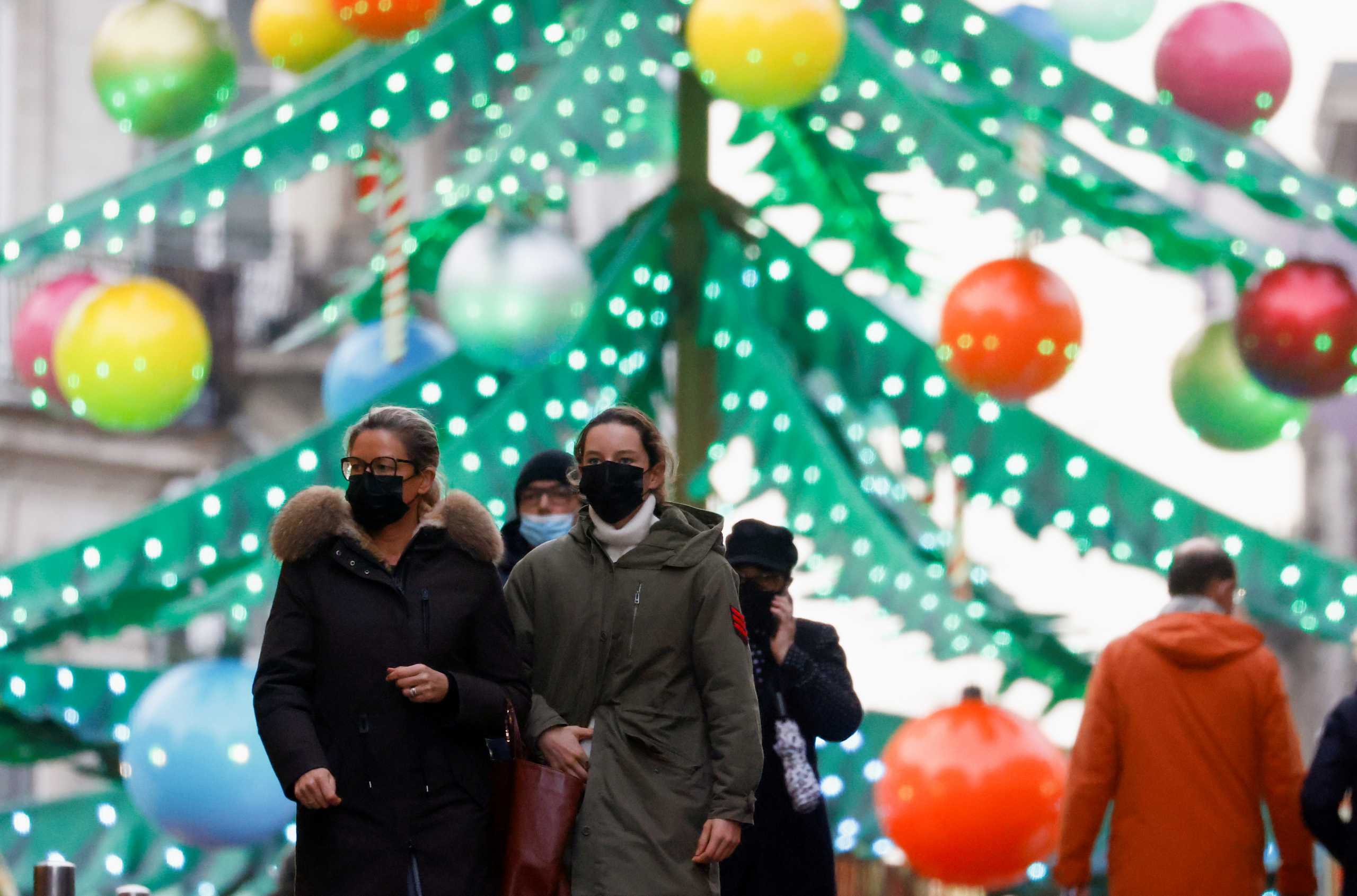 People wearing face masks walk in front of a Christmas tree carousel amid the coronavirus disease (COVID-19) outbreak, in Nantes, in France, December 7, 2021. REUTERS