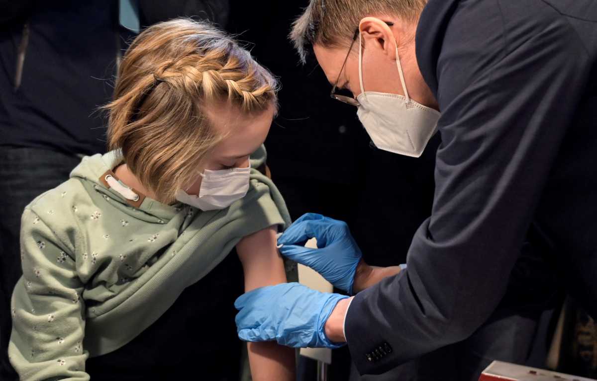 German Health Minister Karl Lauterbach vaccinates Frida, 10, during a visit to a coronavirus disease (COVID-19) vaccination centre in Hanover, Germany, December 17, 2021. REUTERS