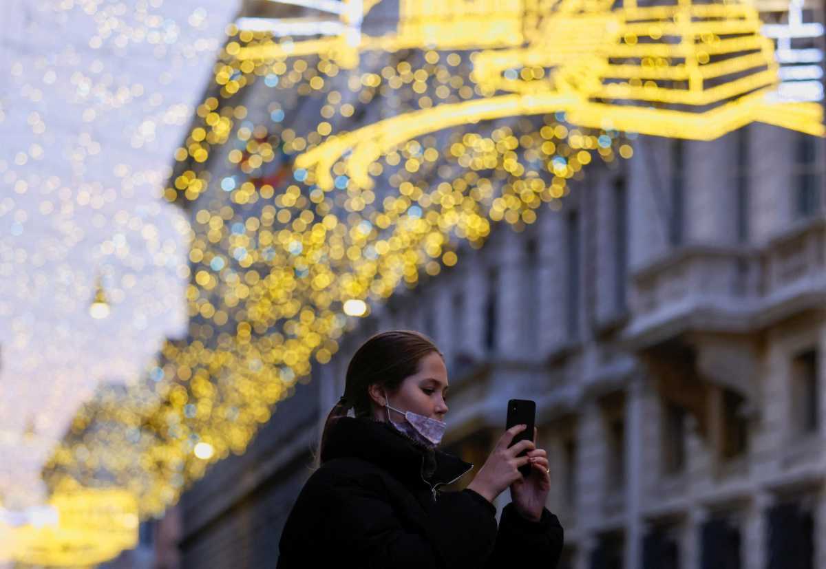A woman takes a picture as she walks in Via del Corso decorated with Christmas lights, in Rome, Italy, December 14, 2021. REUTERS