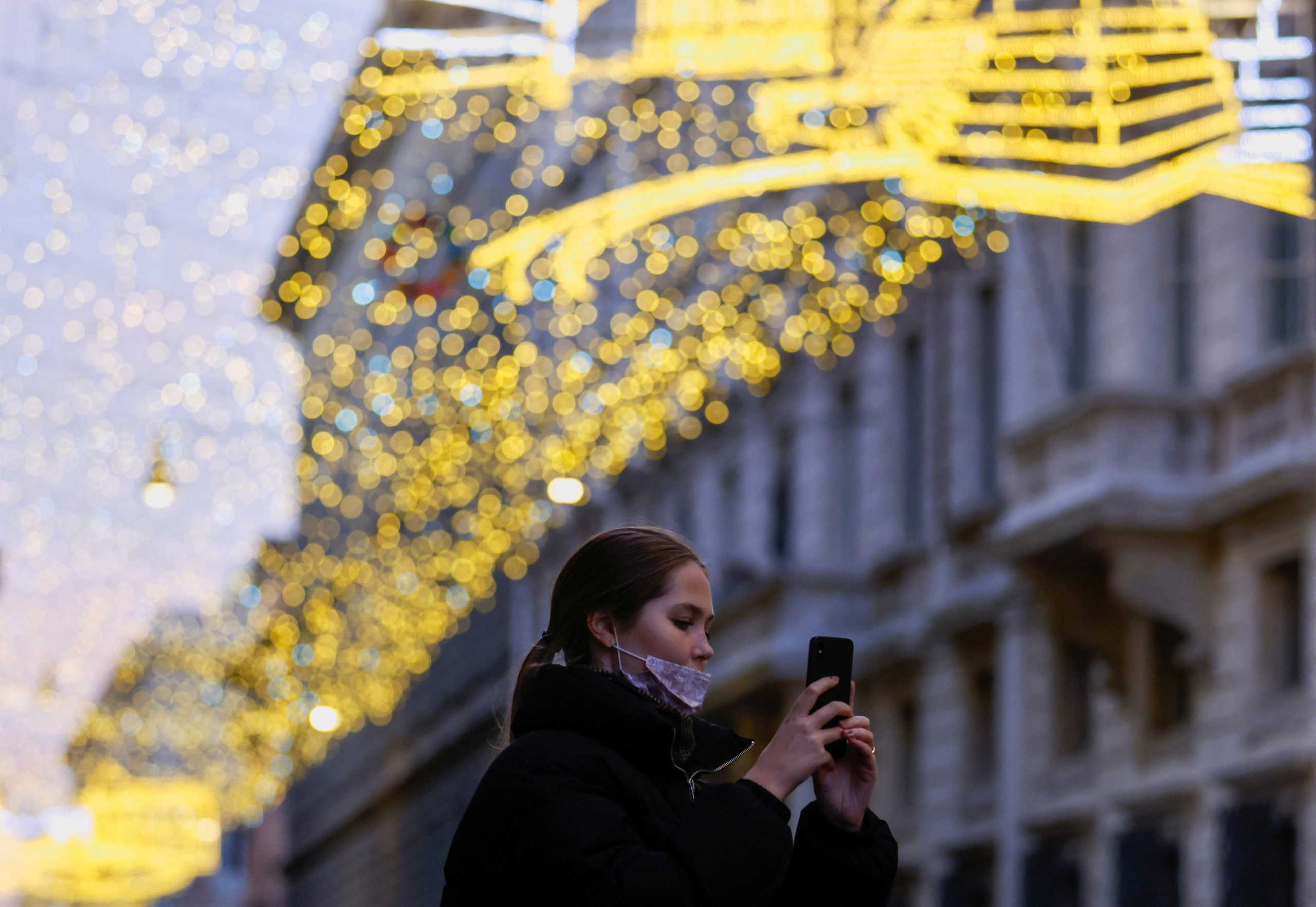 A woman takes a picture as she walks in Via del Corso decorated with Christmas lights, in Rome, Italy, December 14, 2021. REUTERS