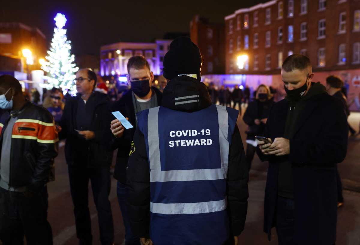 Soccer Football - Premier League - Chelsea v Everton - Stamford Bridge, London, Britain - December 16, 2021 Fans get their coronavirus disease (COVID-19) passes checked outside the stadium before the match REUTERS