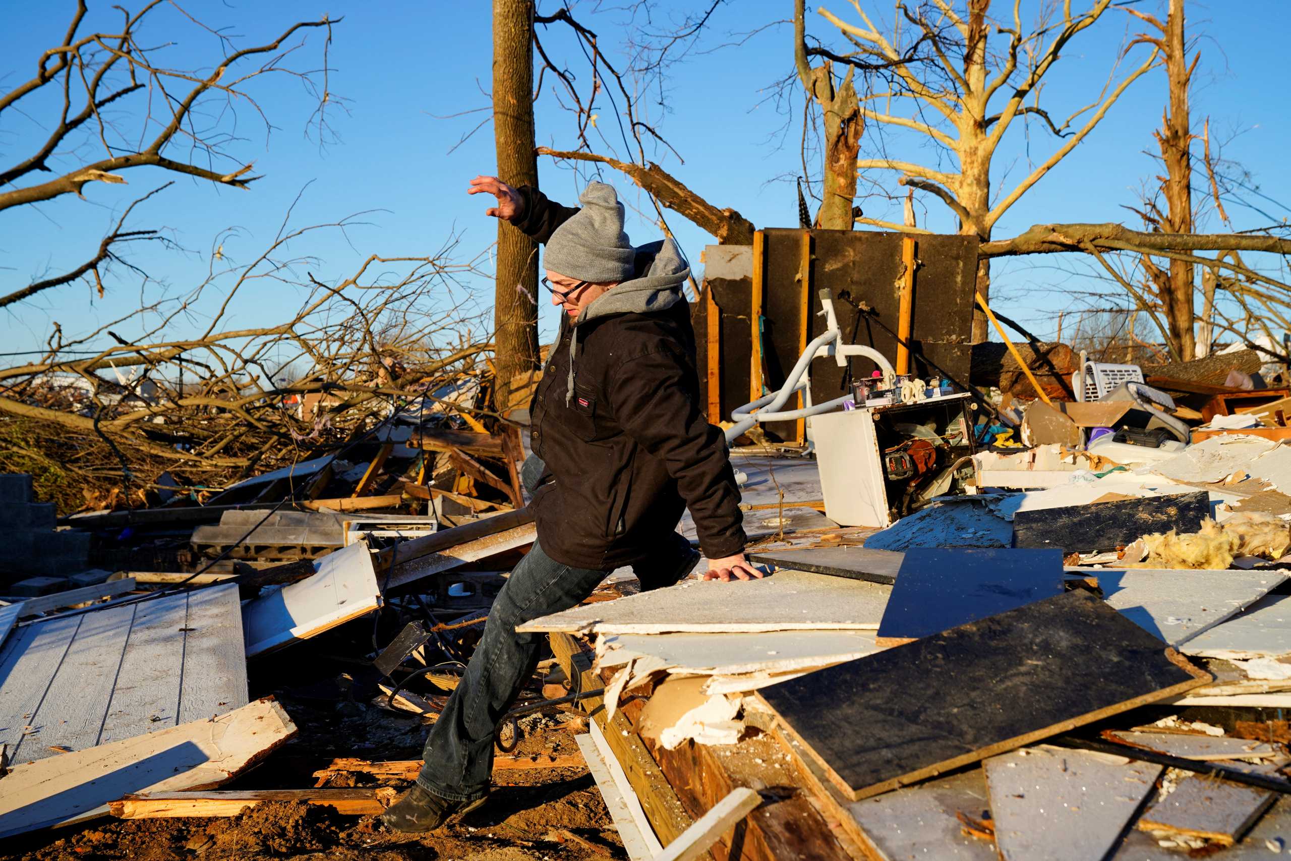 Jeremiah Barker, 37, climbs over the pile of debris where his home once stood, in the aftermath of a tornado in Mayfield, Kentucky, U.S. December 13, 2021. REUTERS
