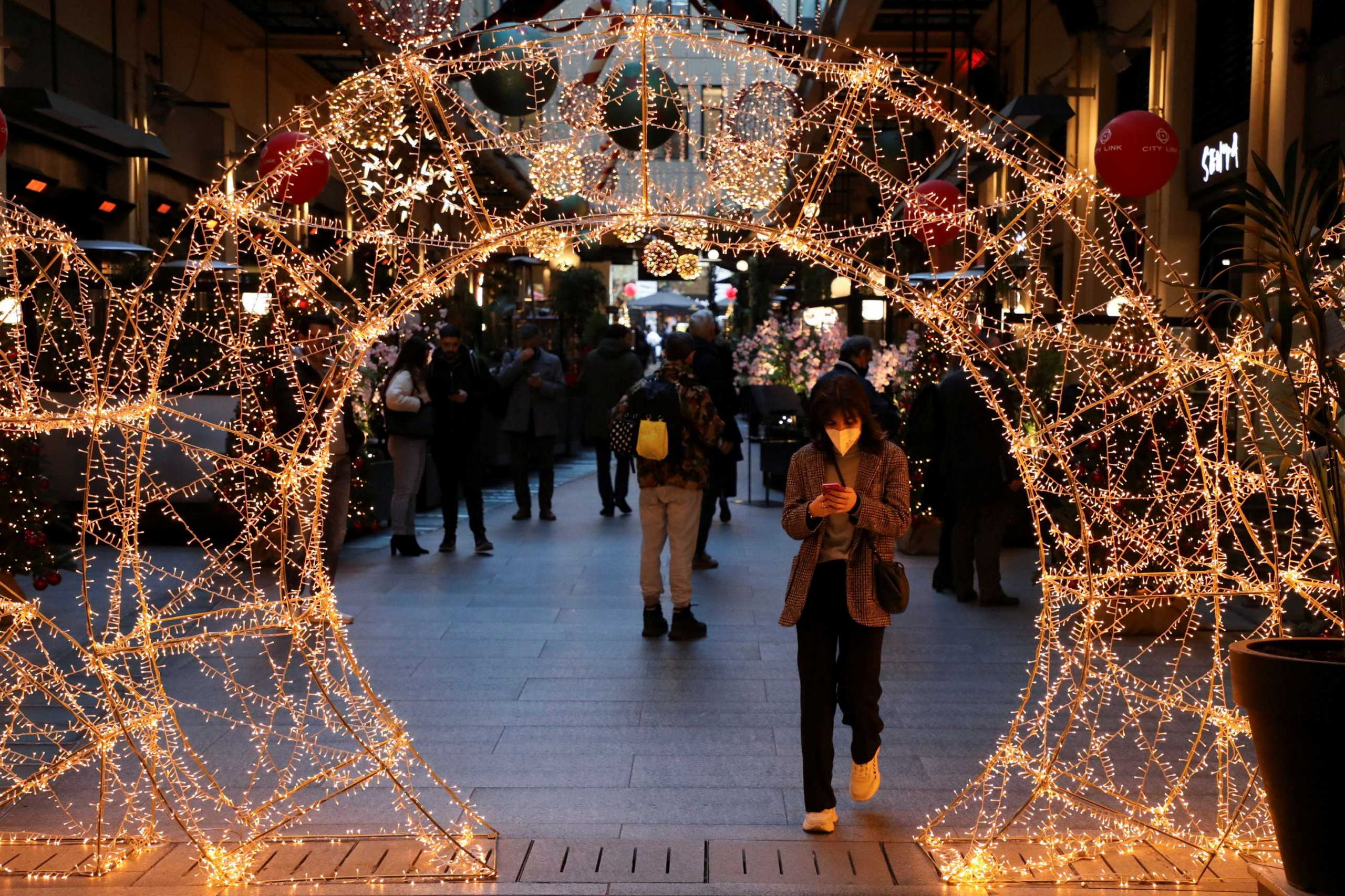 A person wearing a protective face mask makes her way through Christmas decorations as Greece bans public Christmas and New Year's Eve festivities and mandates mask-wearing in open spaces to help curb the spread of the Omicron coronavirus variant, in Athens, Greece, December 23, 2021. REUTERS