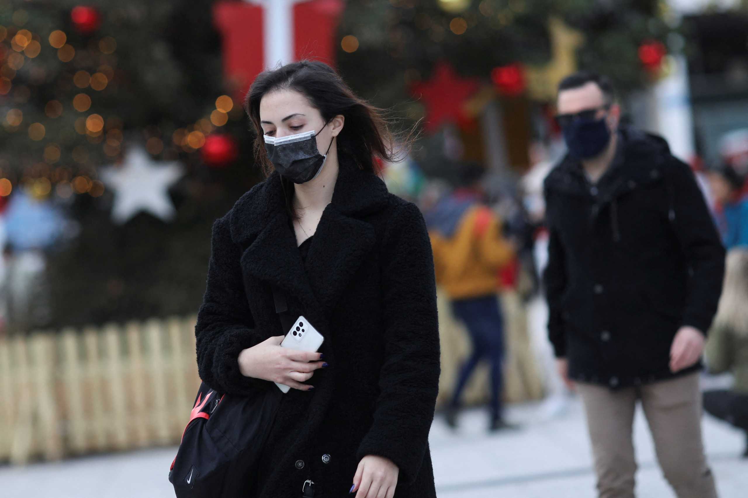 People wearing protective face masks walk by Christmas decorations as Greece bans public Christmas and New Year's Eve festivities and mandates mask-wearing in open spaces to help curb the spread of the Omicron coronavirus variant, in Athens, Greece, December 23, 2021. REUTERS