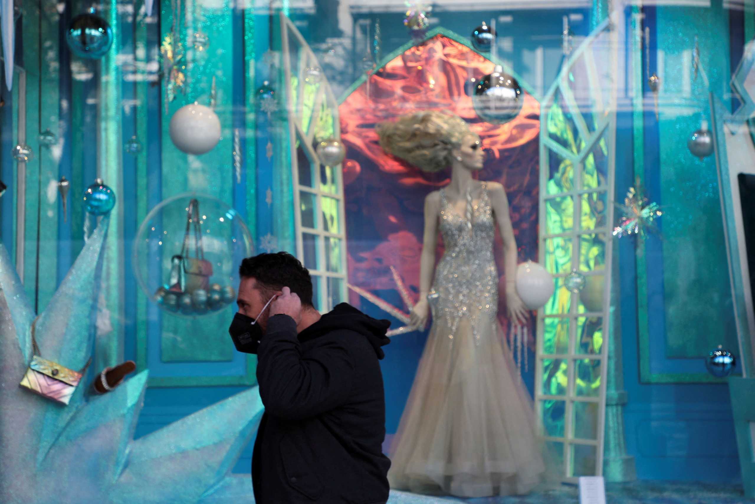 A person puts on his protective face mask in front of Christmas decorations as Greece bans public Christmas and New Year's Eve festivities and mandates mask-wearing in open spaces to help curb the spread of the Omicron coronavirus variant, in Athens, Greece, December 23, 2021. REUTERS