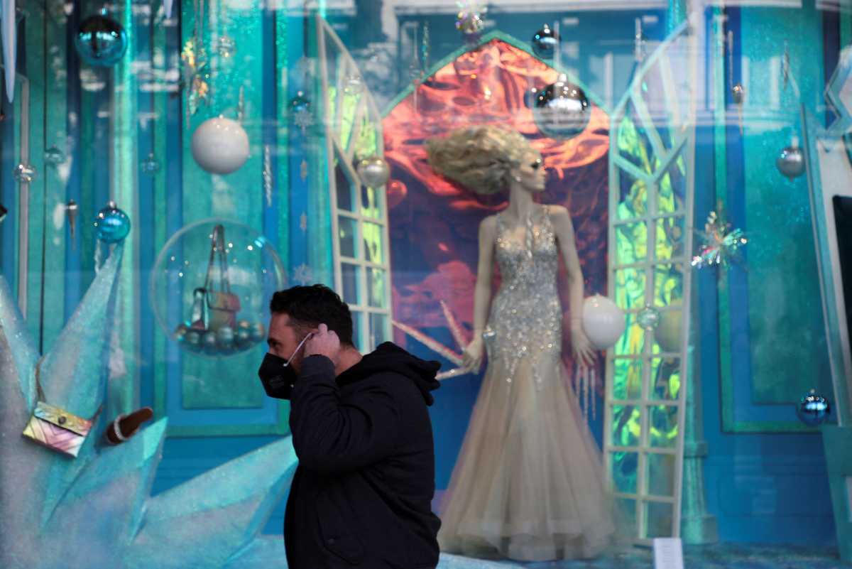 A person puts on his protective face mask in front of Christmas decorations as Greece bans public Christmas and New Year's Eve festivities and mandates mask-wearing in open spaces to help curb the spread of the Omicron coronavirus variant, in Athens, Greece, December 23, 2021. REUTERS