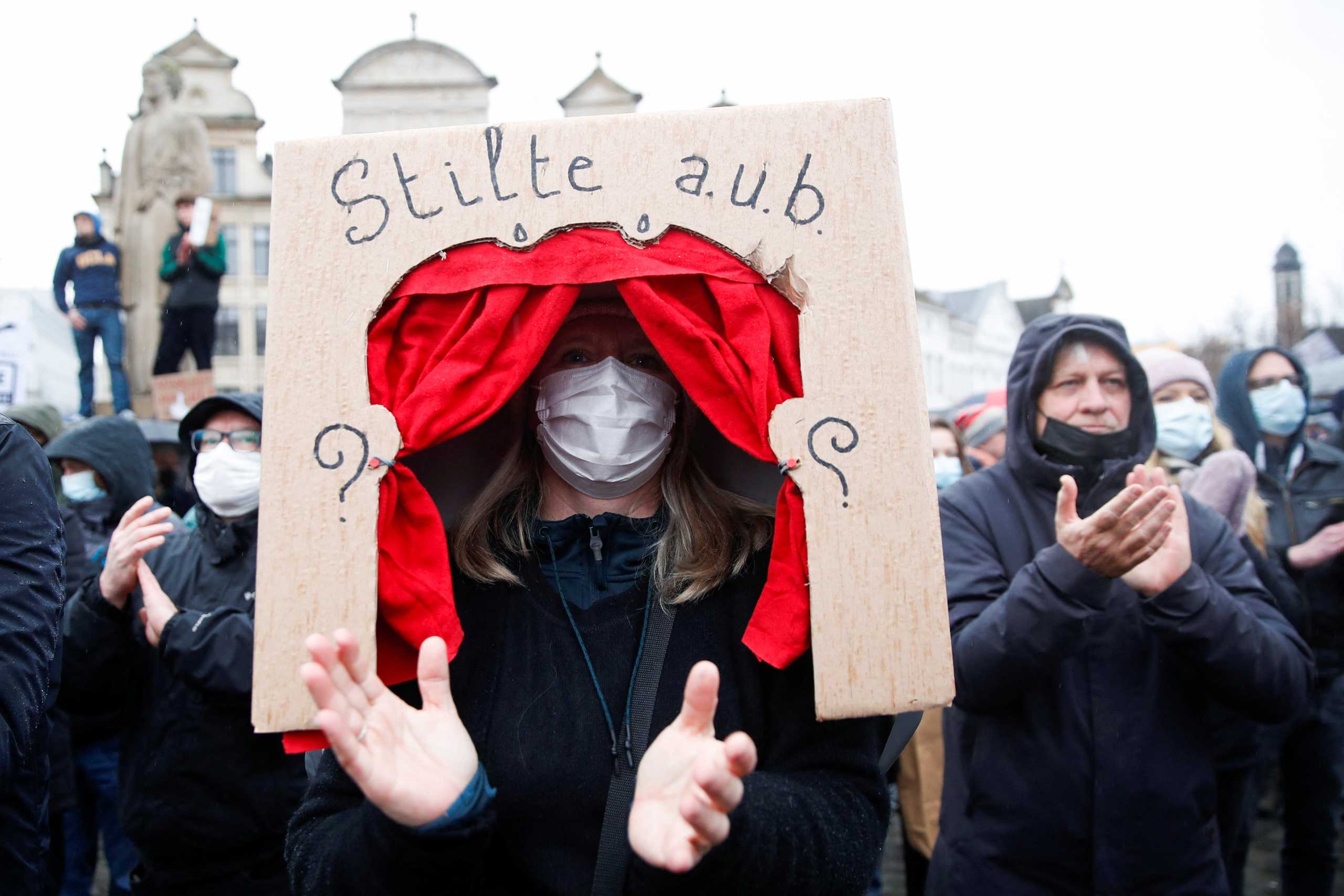 A woman holds a banner reading "Silence please" during a demonstration against the Belgian government's restrictions imposed to contain the spread of coronavirus disease (COVID-19) in Brussels, Belgium December 26, 2021. REUTERS