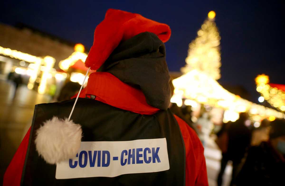 FILE PHOTO: An employe of a Christmas market next to Cologne Cathedral checks a 2G rule status of visitors, as the spread of the coronavirus disease (COVID-19) continues in Cologne, Germany, December 1, 2021. REUTERS