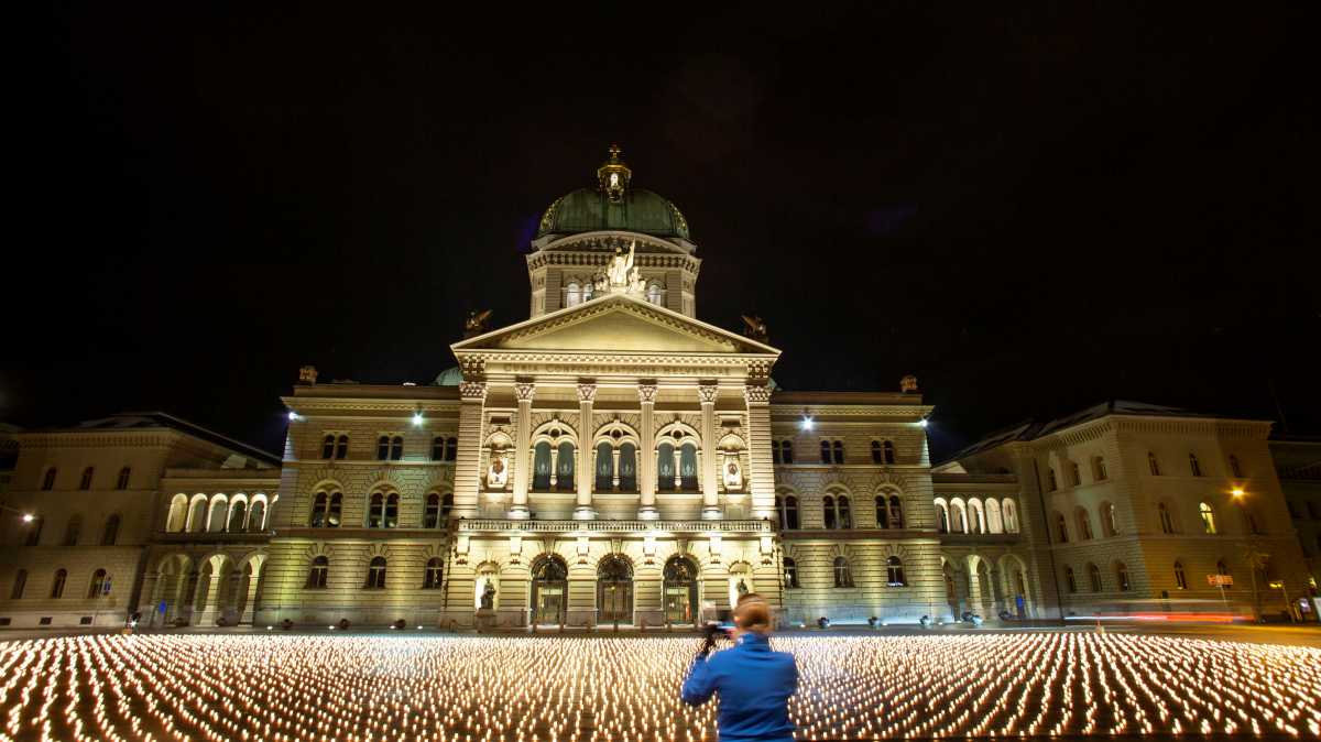 A woman takes a picture of more than 11,000 candles - one for each Swiss victim of the coronavirus disease (COVID-19) pandemic - during a candlelight vigil in front of the seat of the Swiss federal parliament Bundeshaus in Bern, Switzerland December 7, 2021. Picture taken December 7, 2021.    REUTERS