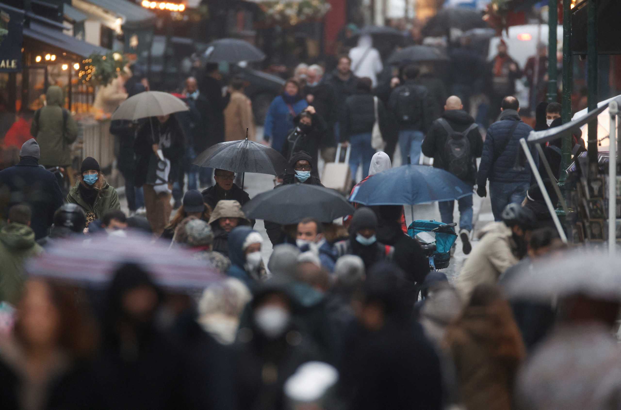 People wearing protective masks are pictured on a rainy winter day in the Montorgueil street, amid the spread of the coronavirus disease (COVID-19) pandemic, in Paris, France, December 27, 2021. REUTERS