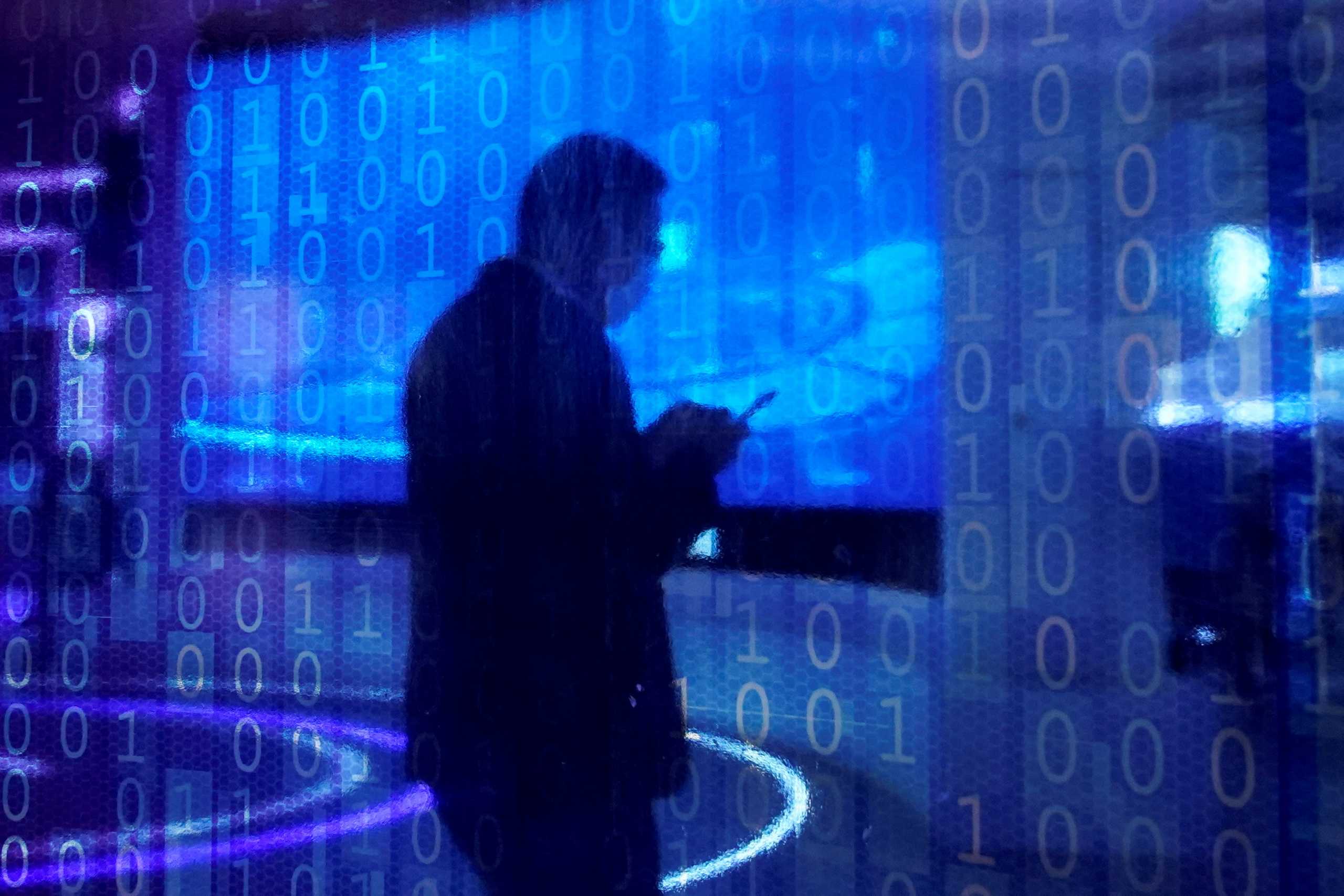 FILE PHOTO: A man looking at a phone is seen through a digitally decorated glass during the World Internet Conference (WIC) in Wuzhen, Zhejiang province, China, November 23, 2020. REUTERS