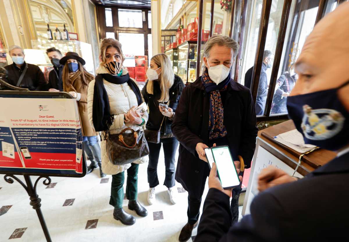 A customer has his coronavirus disease (COVID-19) health pass, known as a Green Pass, checked as he arrives at a bar the day the government restricts access of unvaccinated to indoor venues, in Naples, Italy December 6, 2021. REUTERS